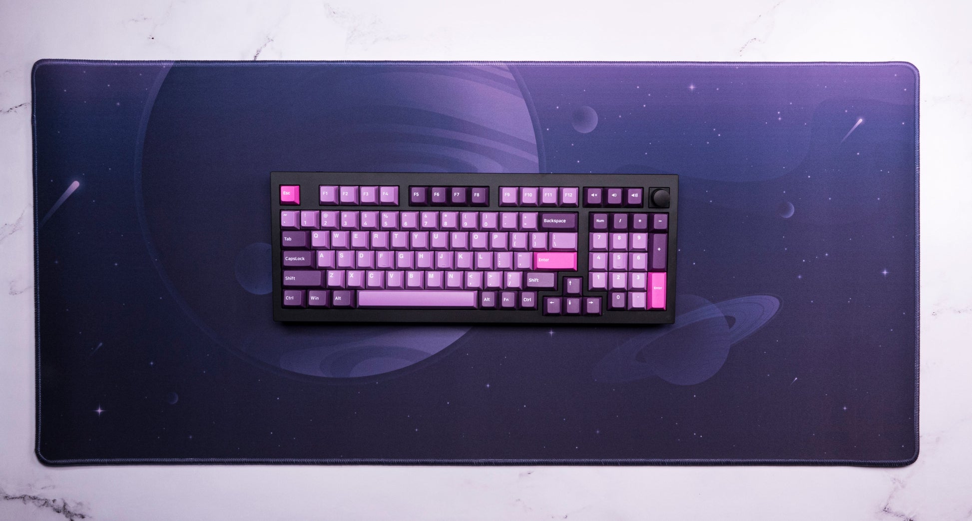 Desk mat with dark purple space print and a keyboard centered on top