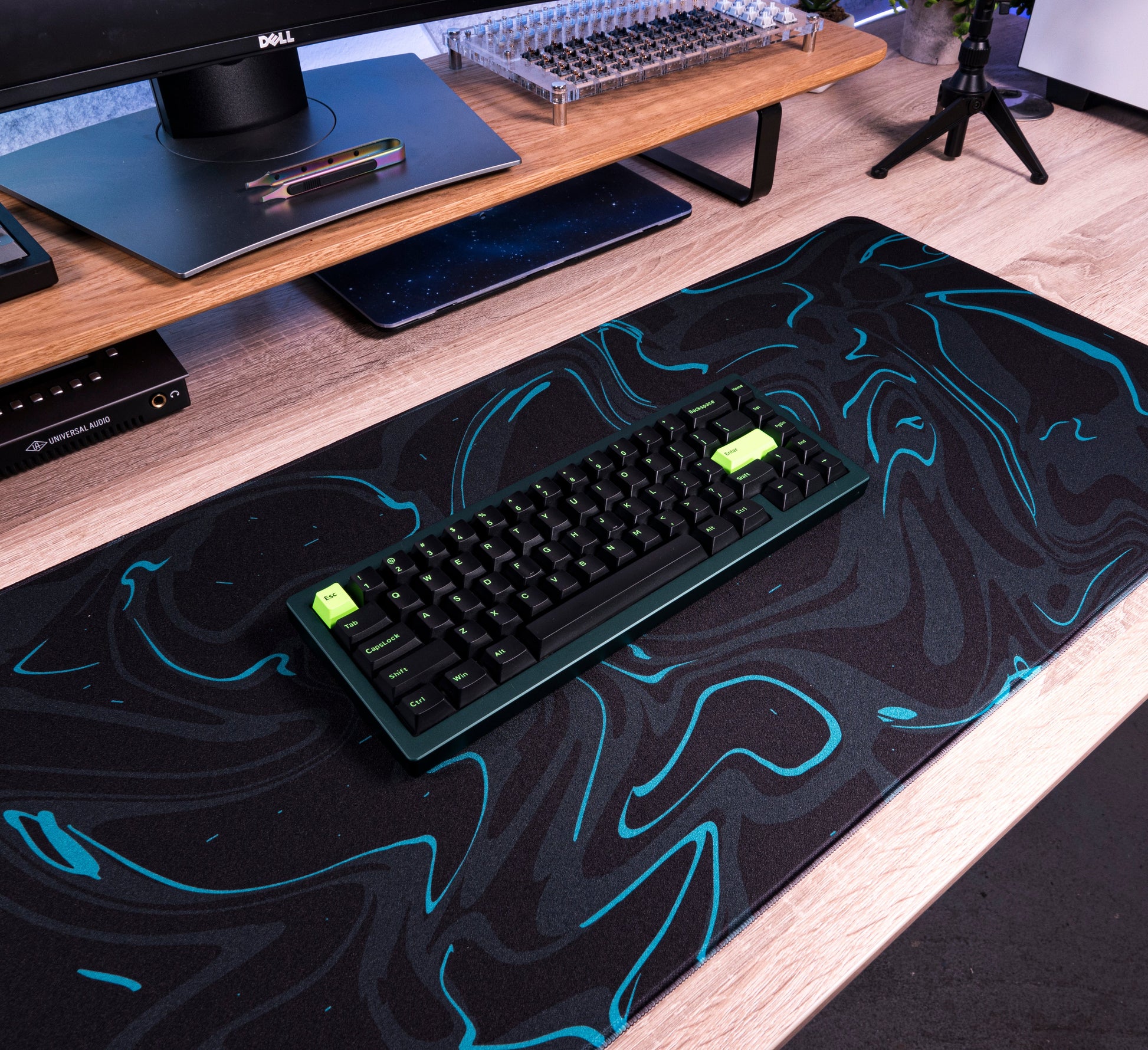 Black desk mat with teal marble swirl design and full-size keyboard on top
