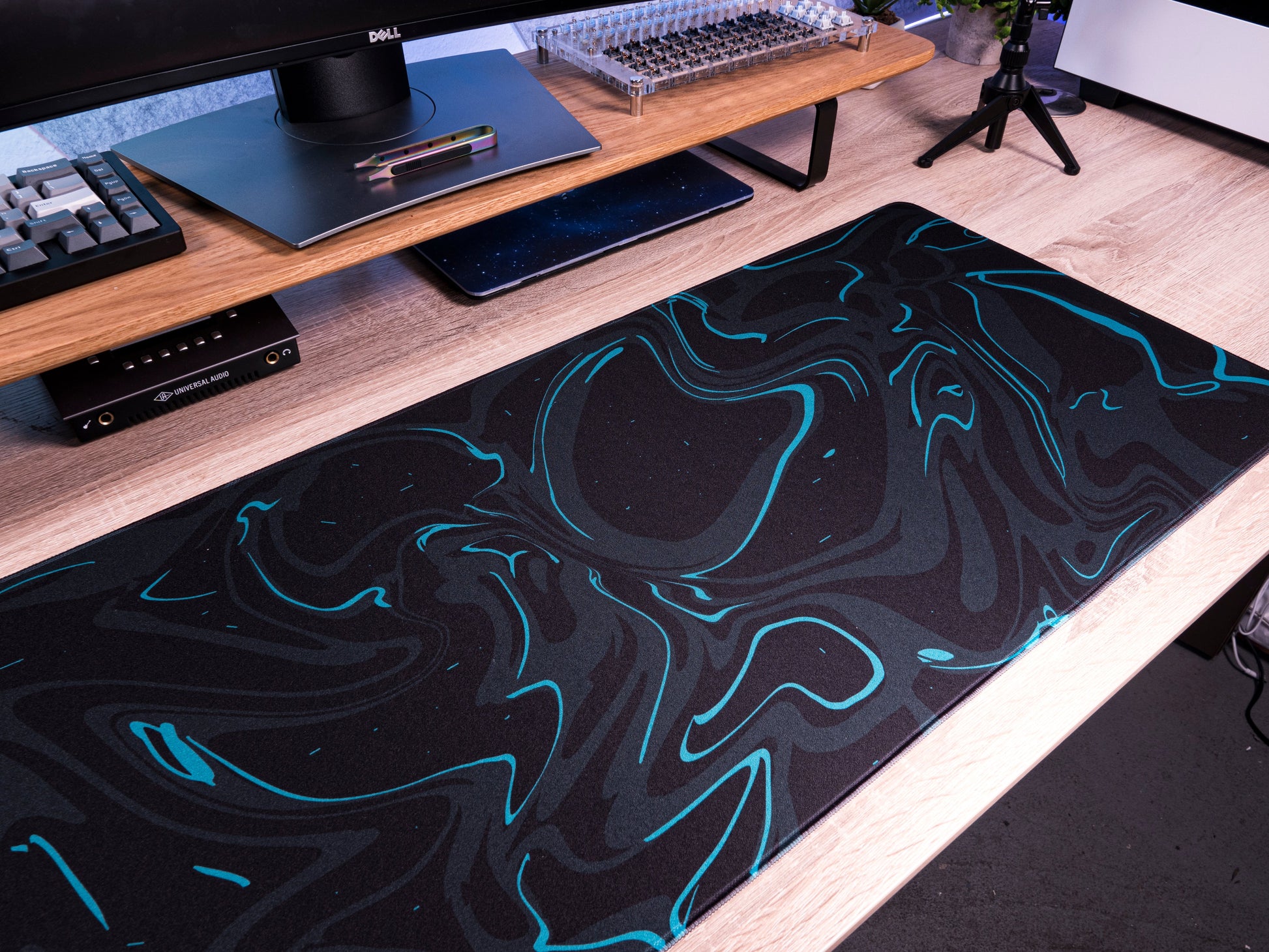 Black desk mat with teal marble swirl pattern spread across a desk