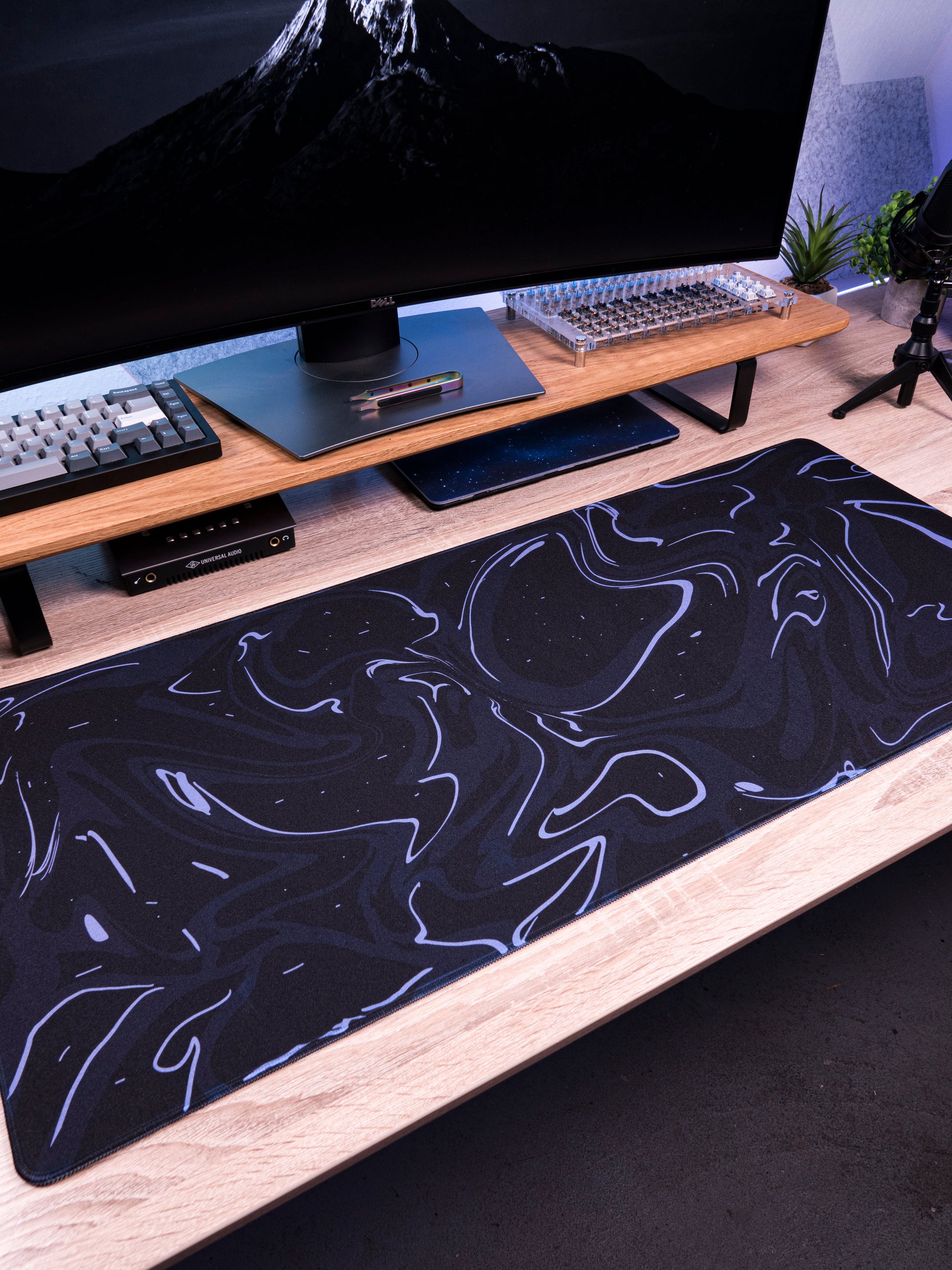 Dark navy desk mat with light purple marble swirl pattern on a workstation
