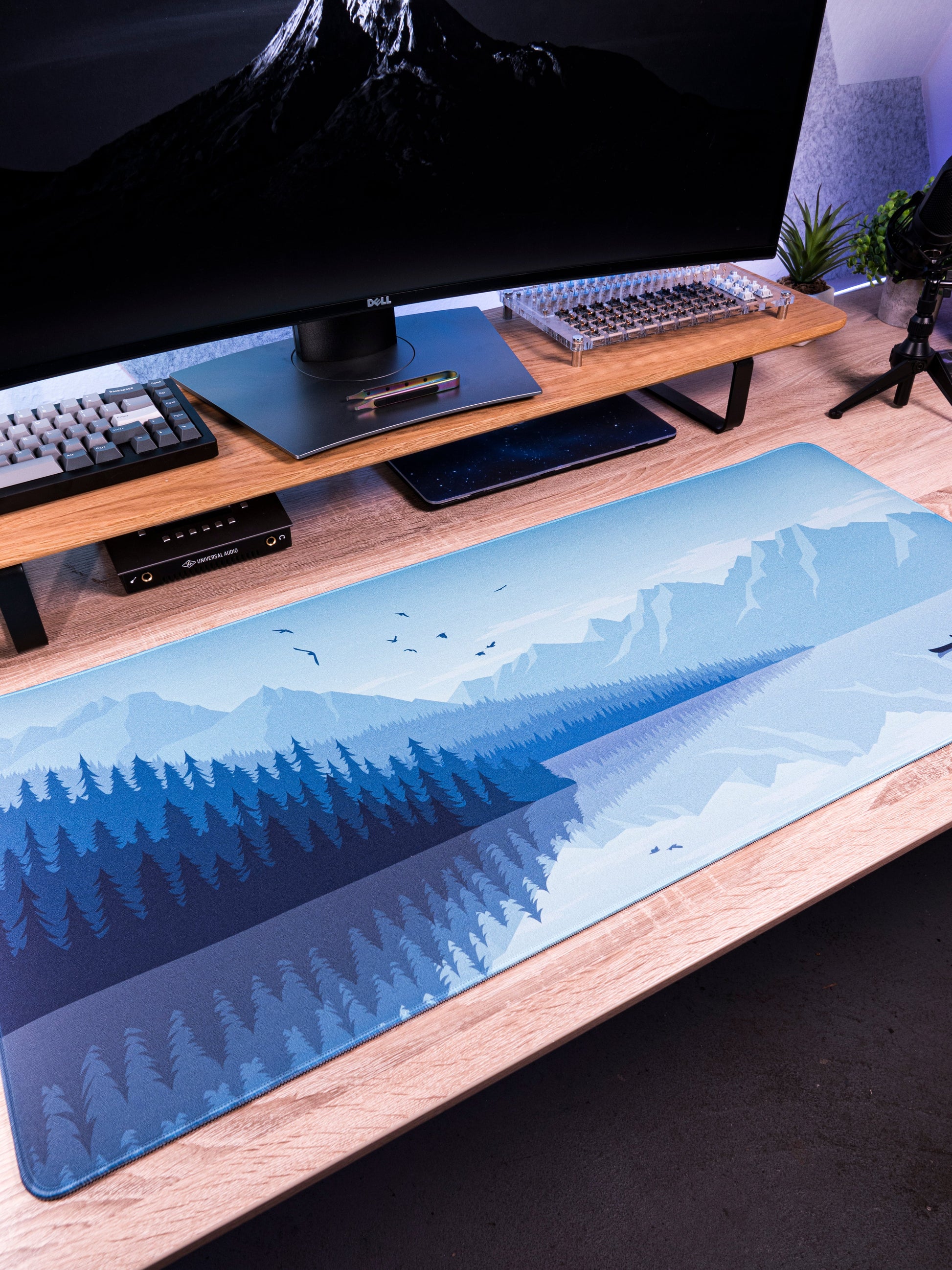 Alberta V2 desk mat with light blue mountain and pine forest print along desk