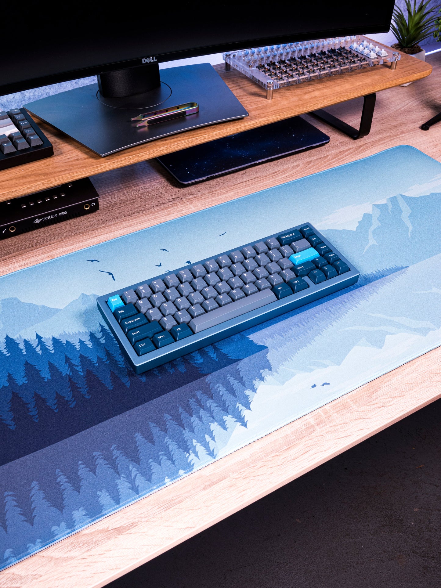 Blue desk mat with snowy mountain and pine landscape print, flat top surface
