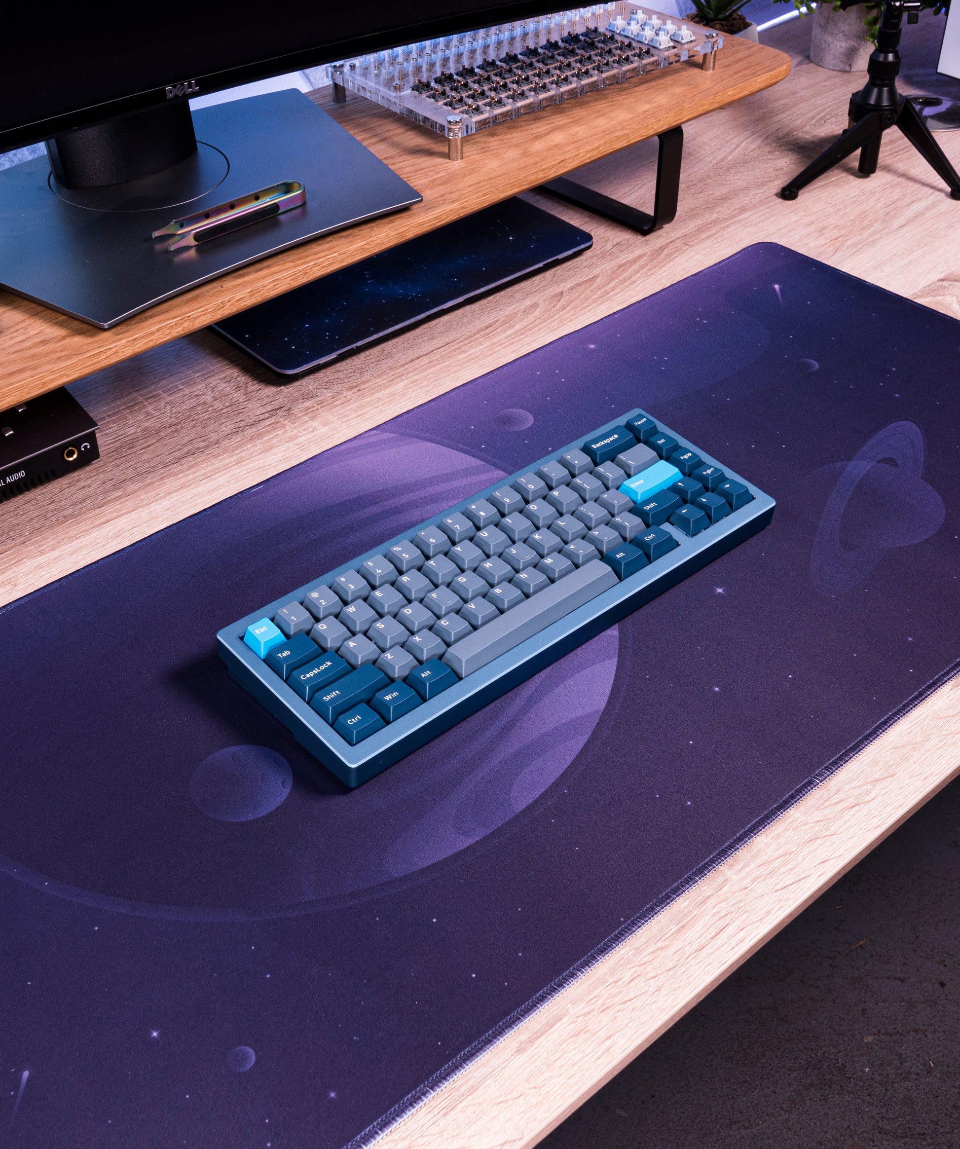 Desk mat in dark purple with space print under a keyboard on a wooden desk
