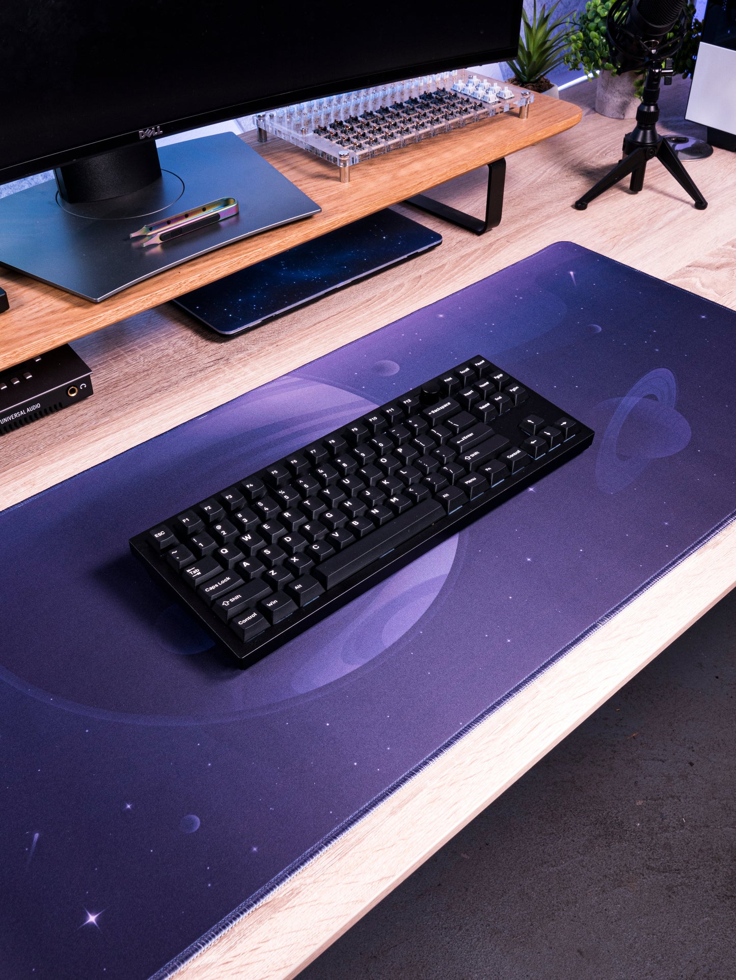 Desk mat with dark purple space print and a black keyboard on a desk