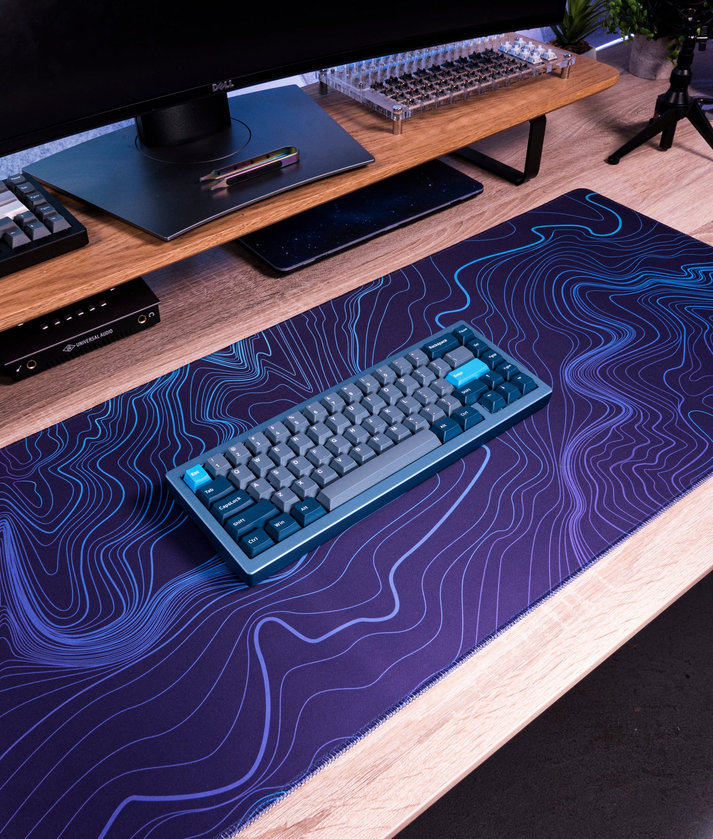Purple-blue desk mat with blue contour line topographic design under a keyboard
