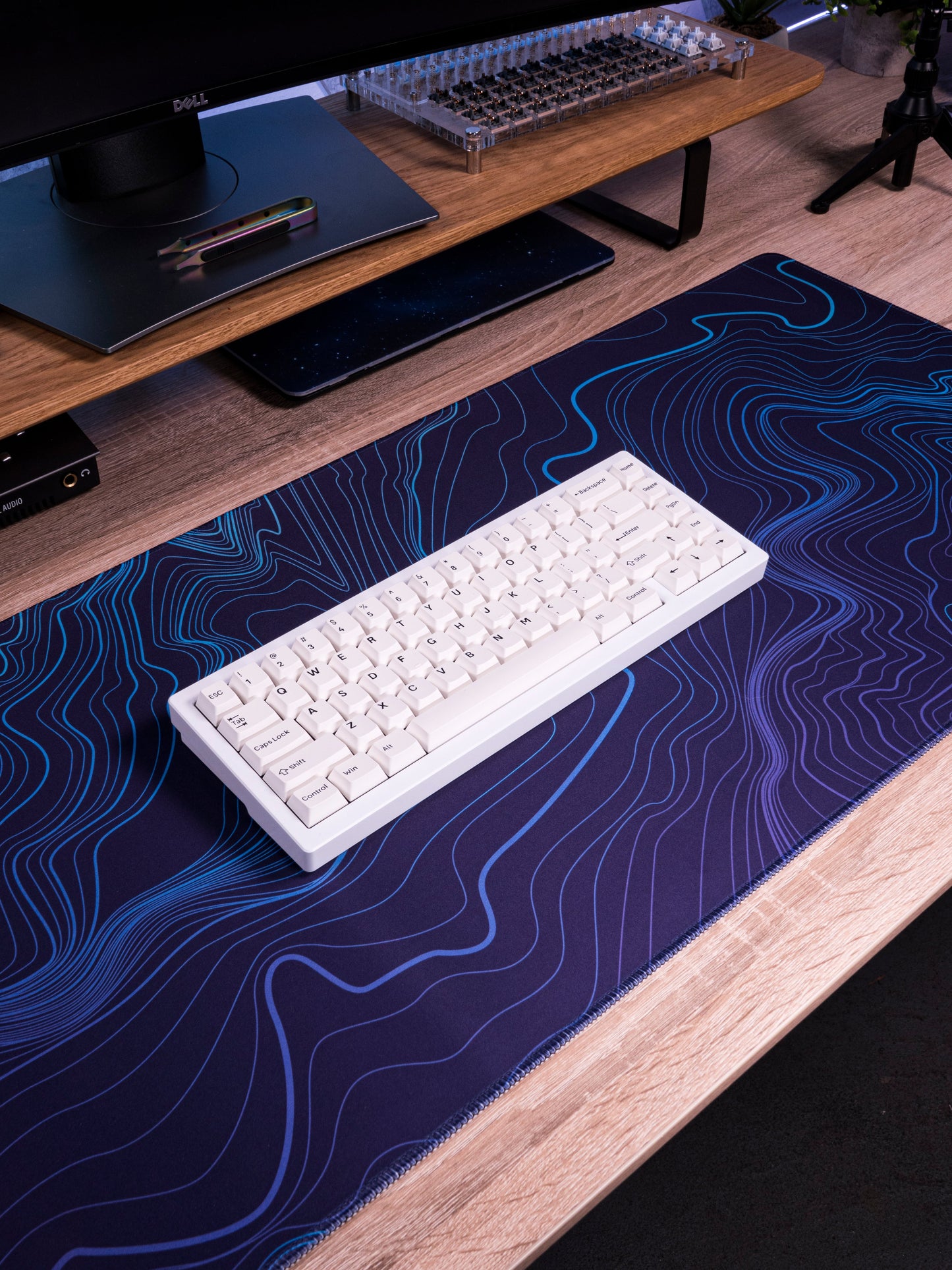 Purple-blue desk mat with blue topographic contour lines beneath a white keyboard