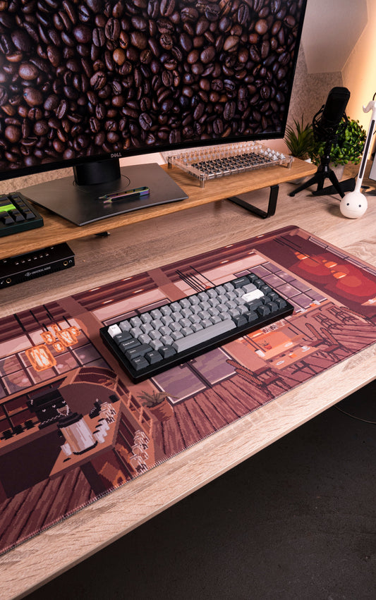Desk mat with coffee shop artwork, keyboard and desk items on surface