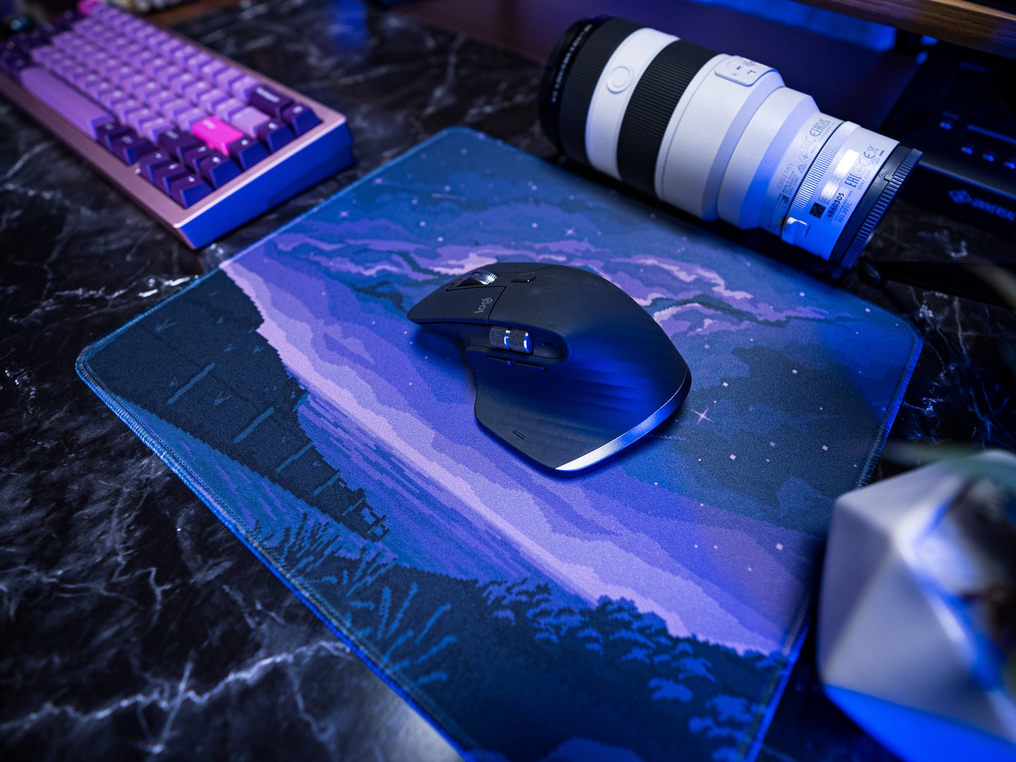Blue pixel desk mat with starry landscape and a mouse on top