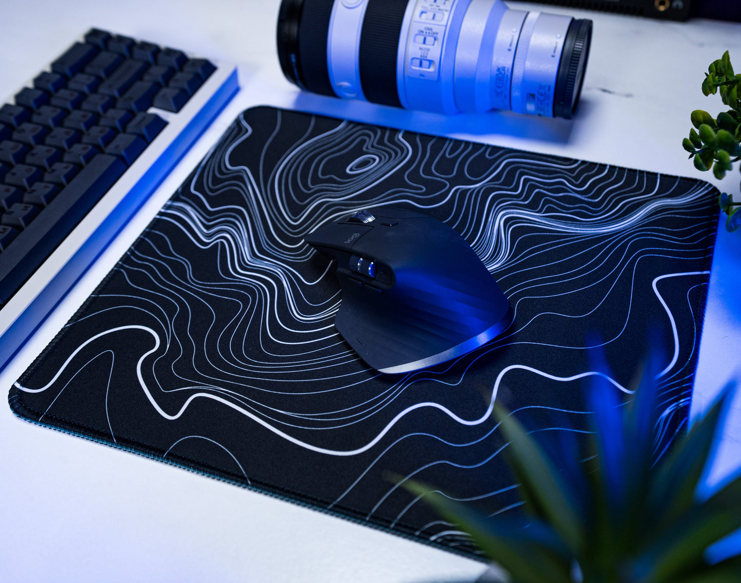 Black desk mat with white topographic line pattern, black mouse on surface