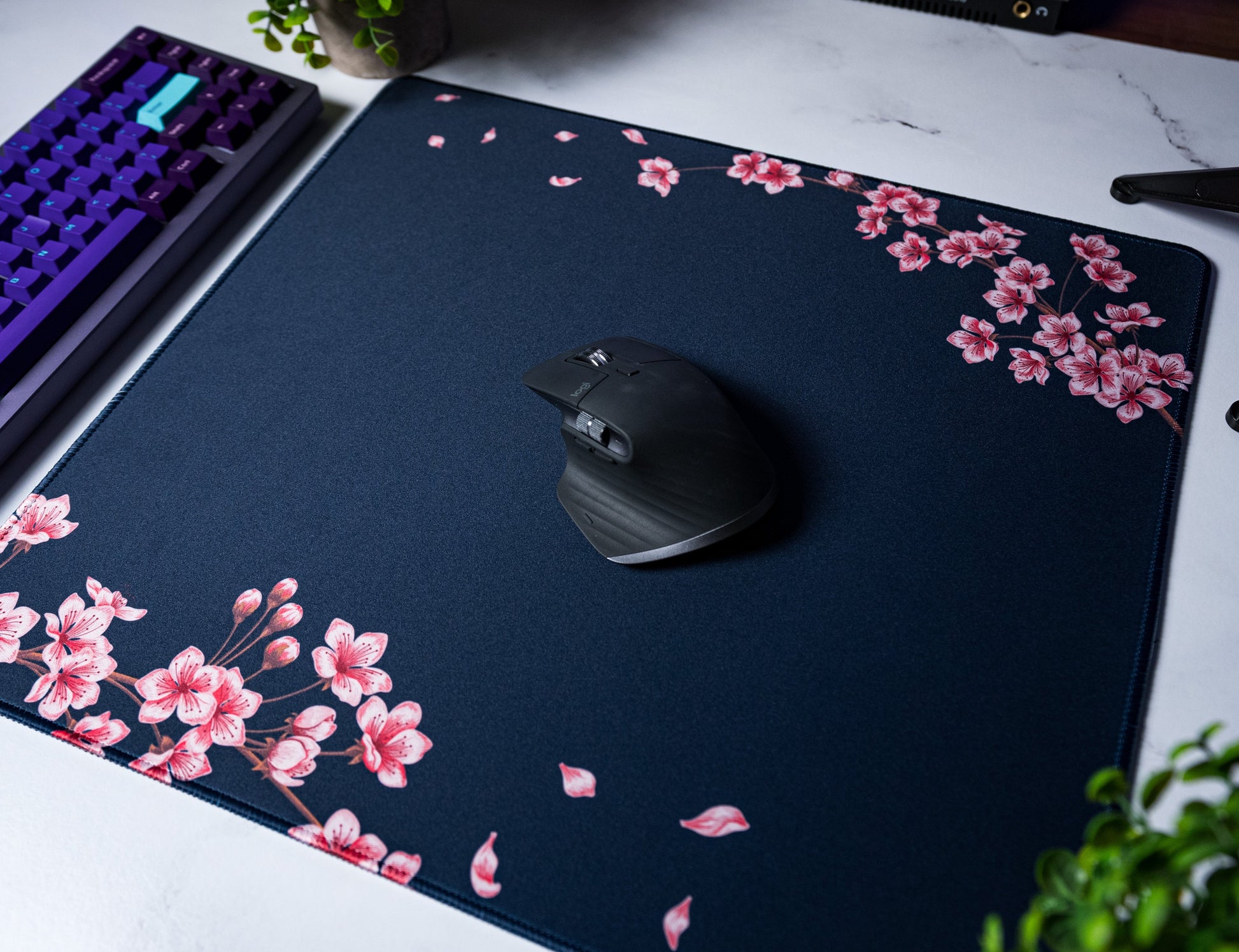 Navy desk mat with pink floral corner print and scattered leaf specks; stitched edge