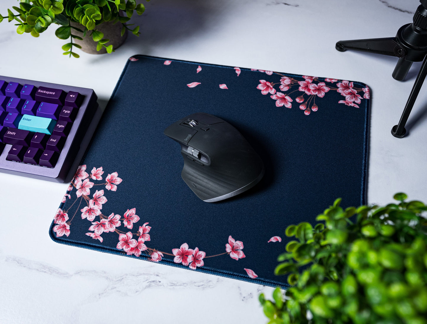Navy desk mat with pink blossom branches and leaf specks; stitched border