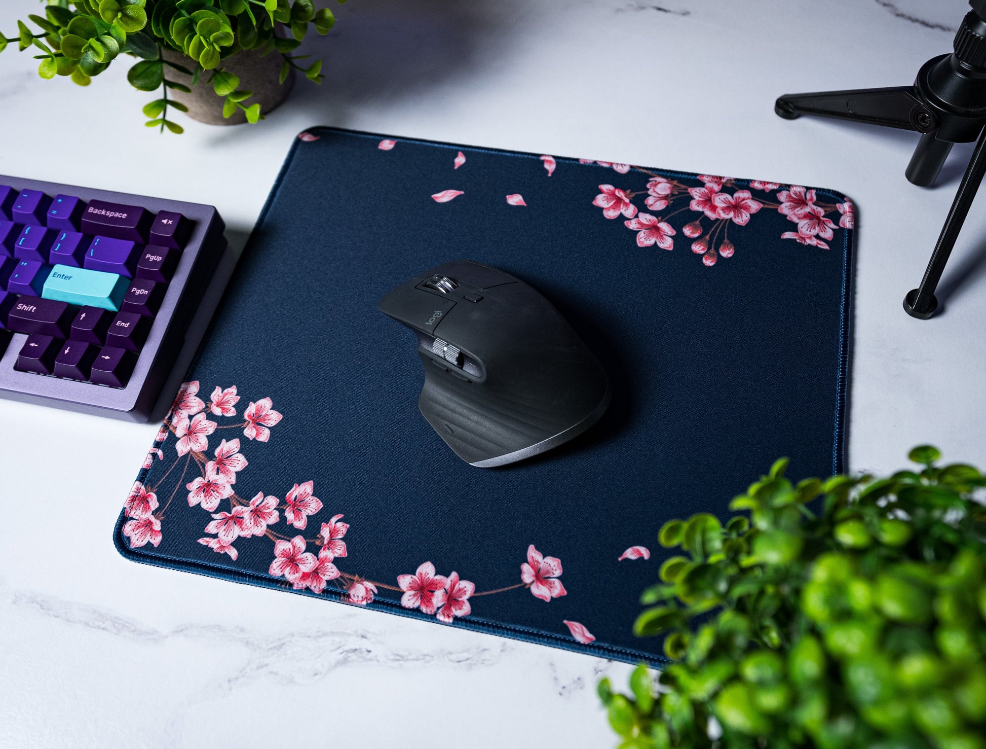 Navy desk mat with pink blossom branches and leaf specks; stitched border
