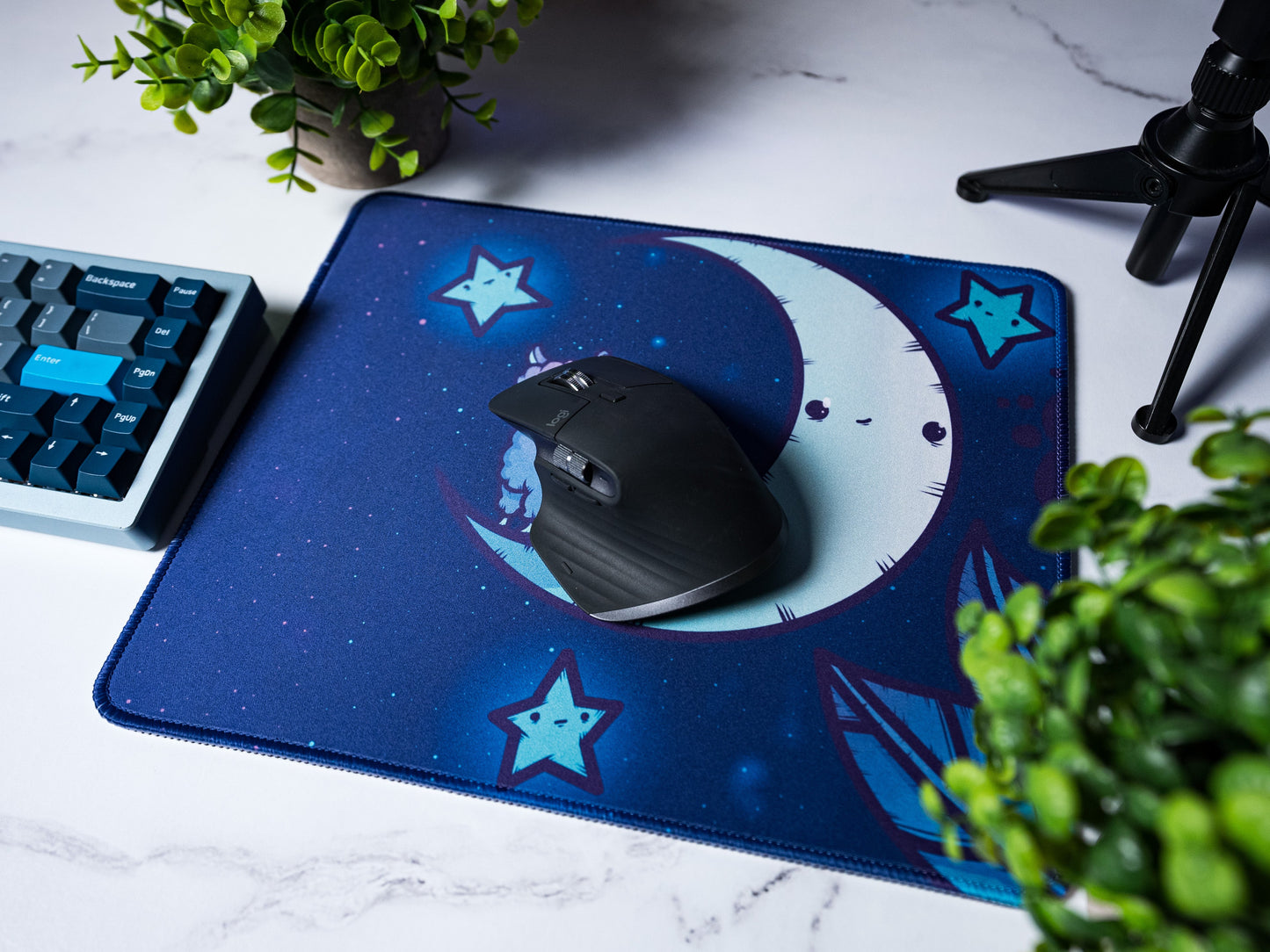 Blue desk mat with alpaca and crescent moon; black computer mouse on top