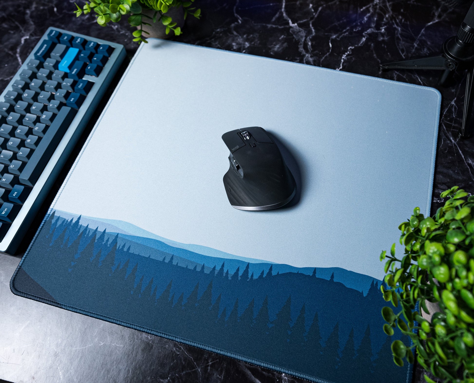 Large desk mat with blue forest horizon graphic, mouse centered on it