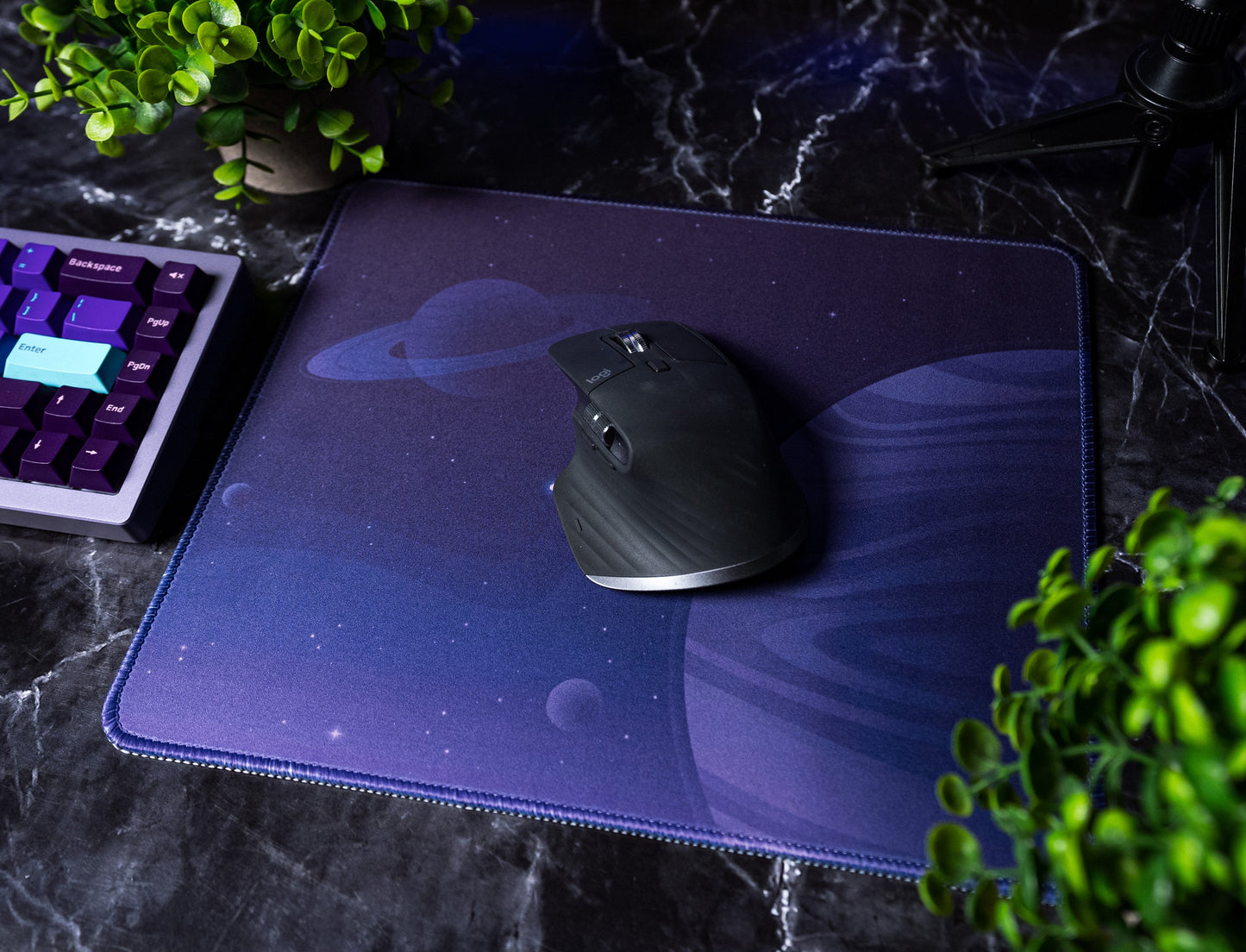 Desk mat with dark purple space print and a black mouse angled on top
