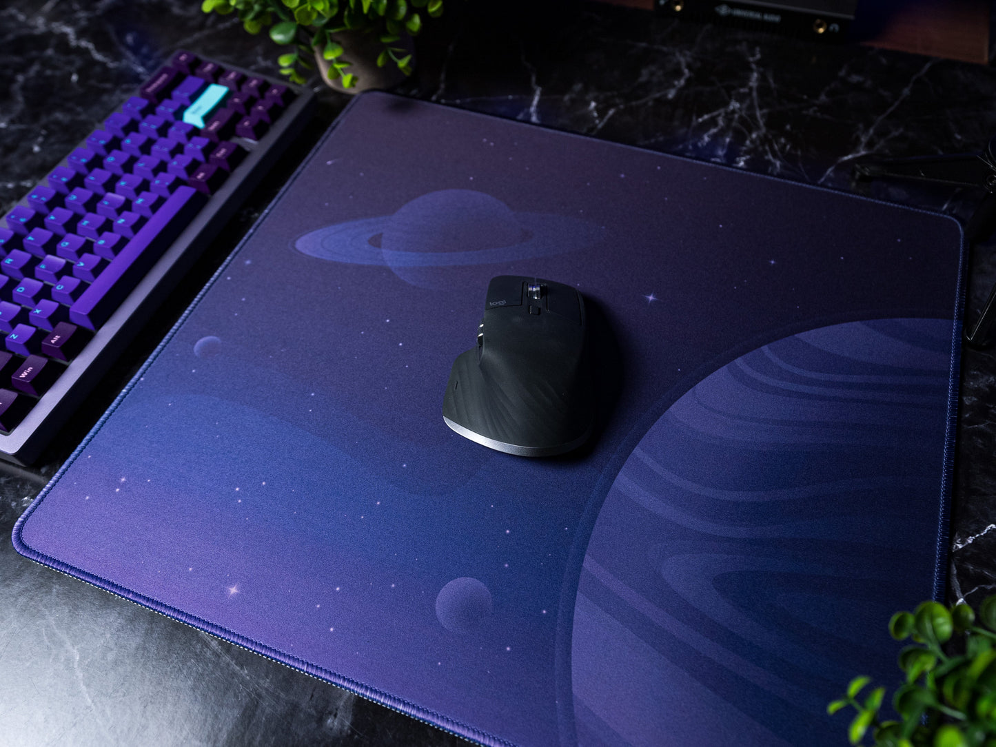 Desk mat with dark purple space print and a black mouse on top