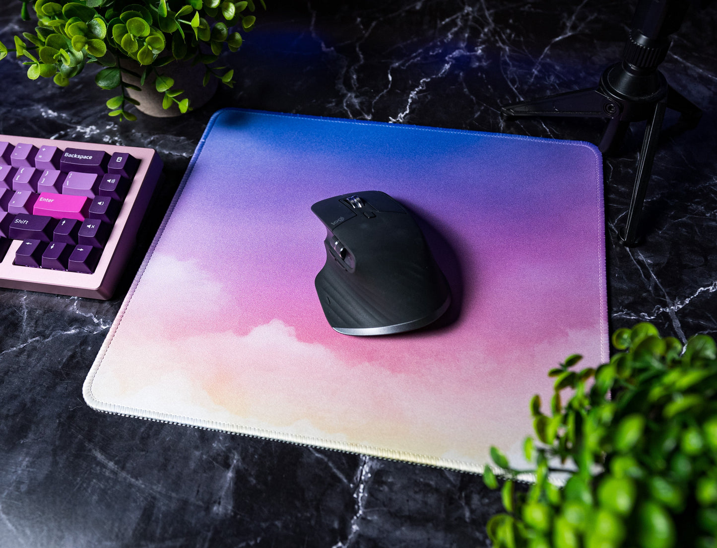 Square desk mat with pastel clouds and stitched edge, featuring a black mouse