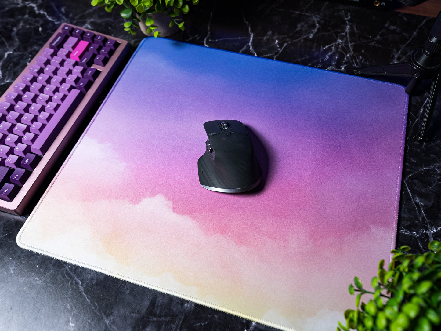 Desk mat with pastel cloud gradient and white stitched border, with a black mouse