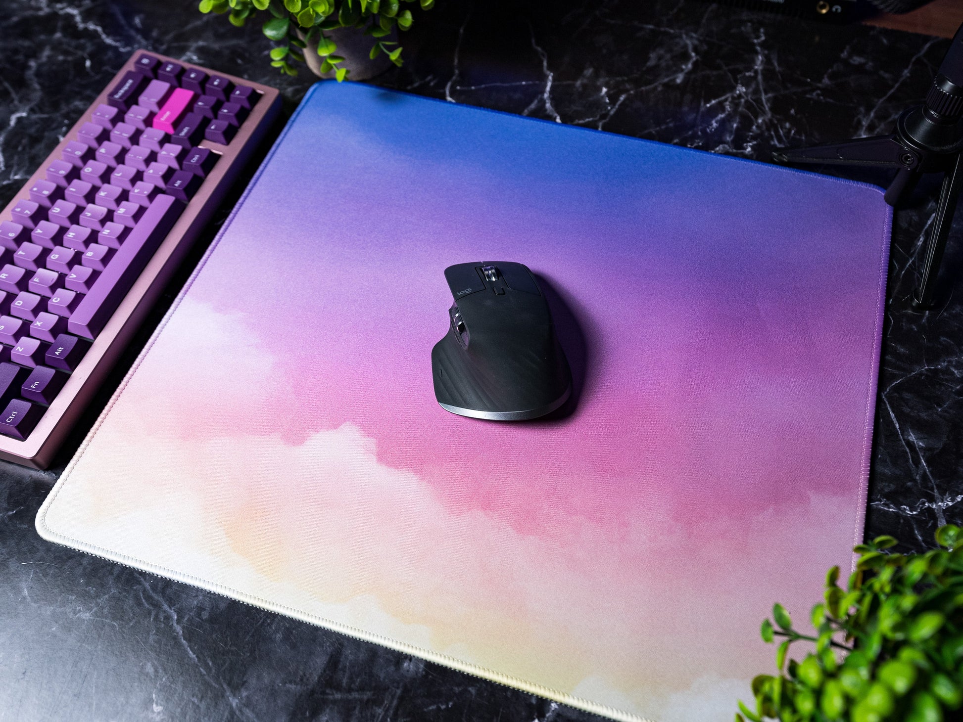Desk mat with pastel cloud gradient and white stitched border, with a black mouse