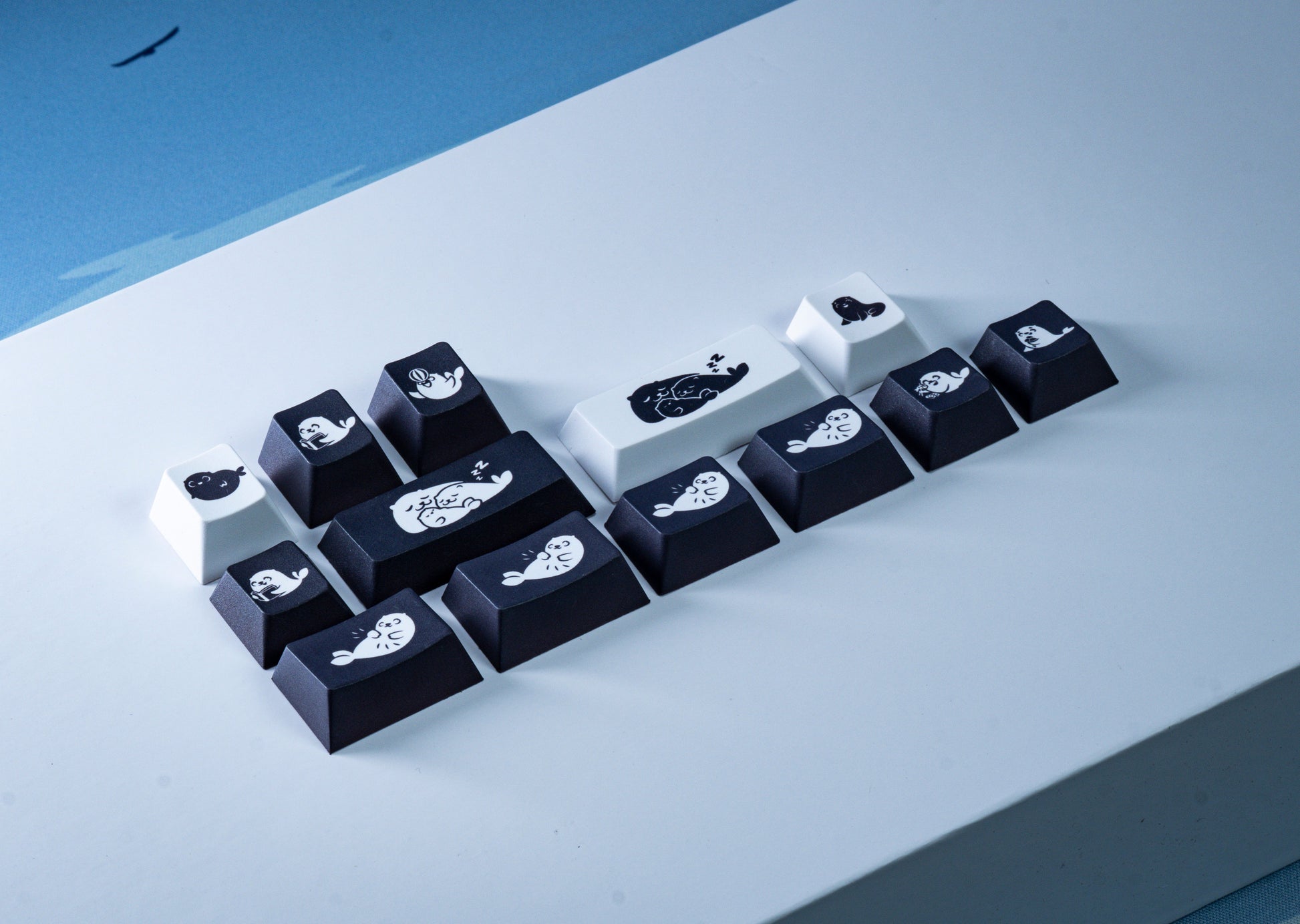 Keycap set with dark and white keycaps featuring seal icons and paw-print designs