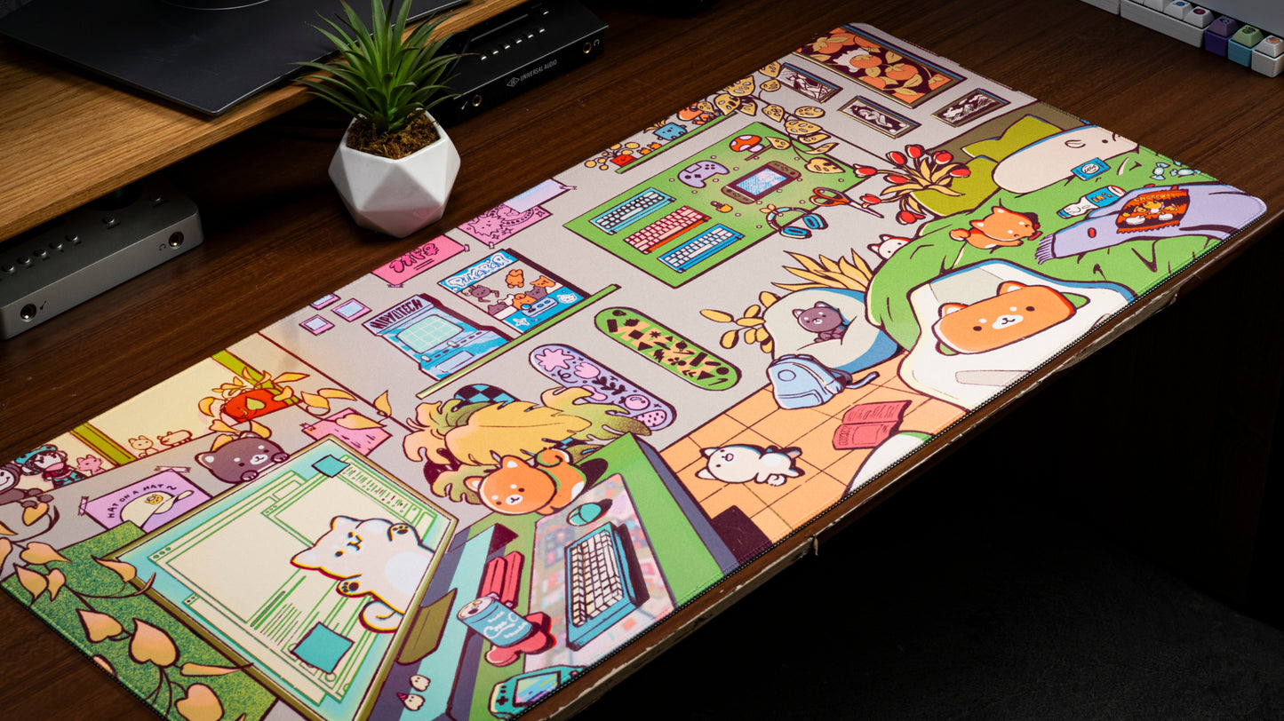 Cartoon gaming desk mat with animal characters and devices, stitched border visible