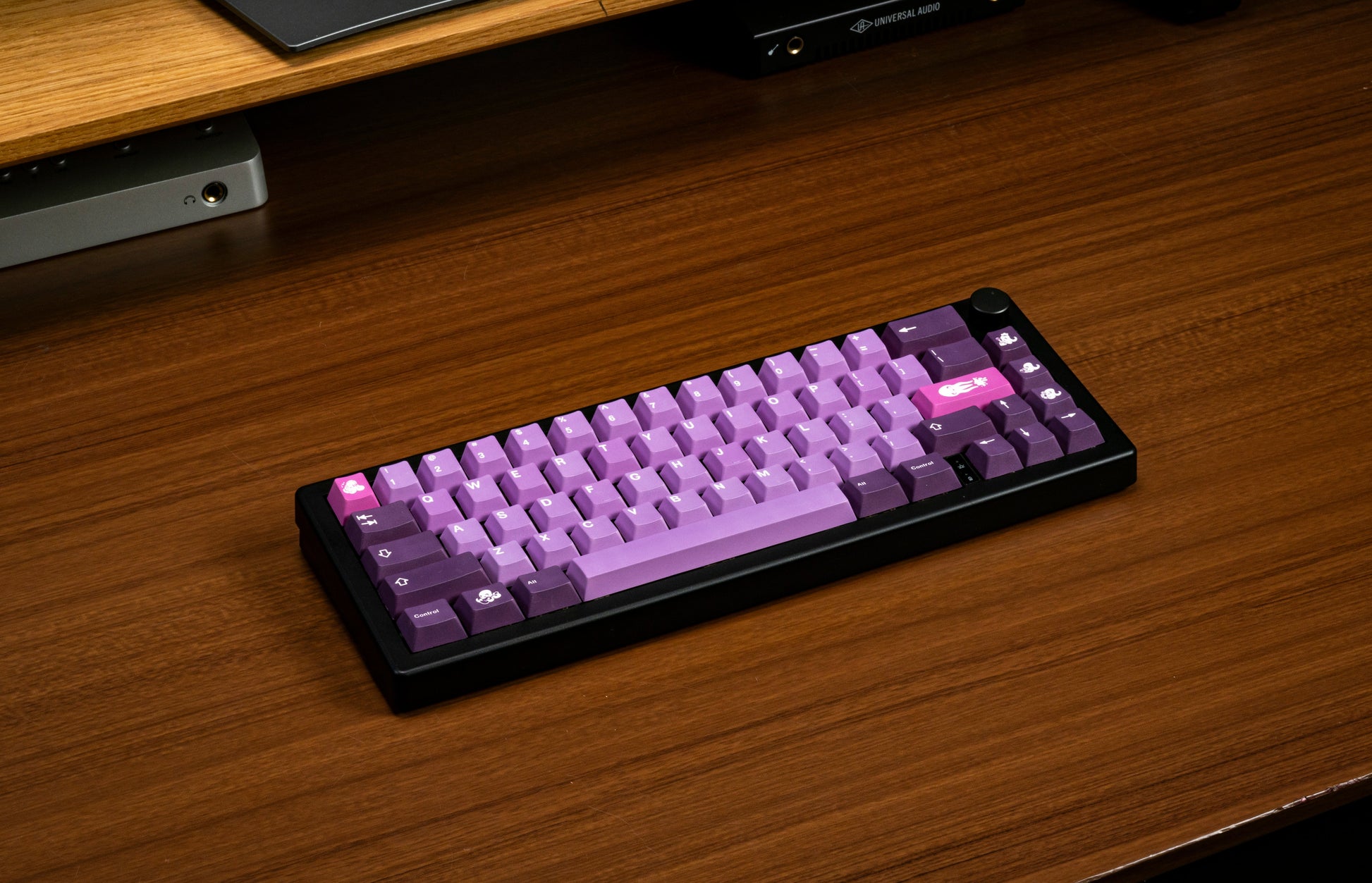 Purple octopus-themed keycaps keyboard on a wood desk, angled view.