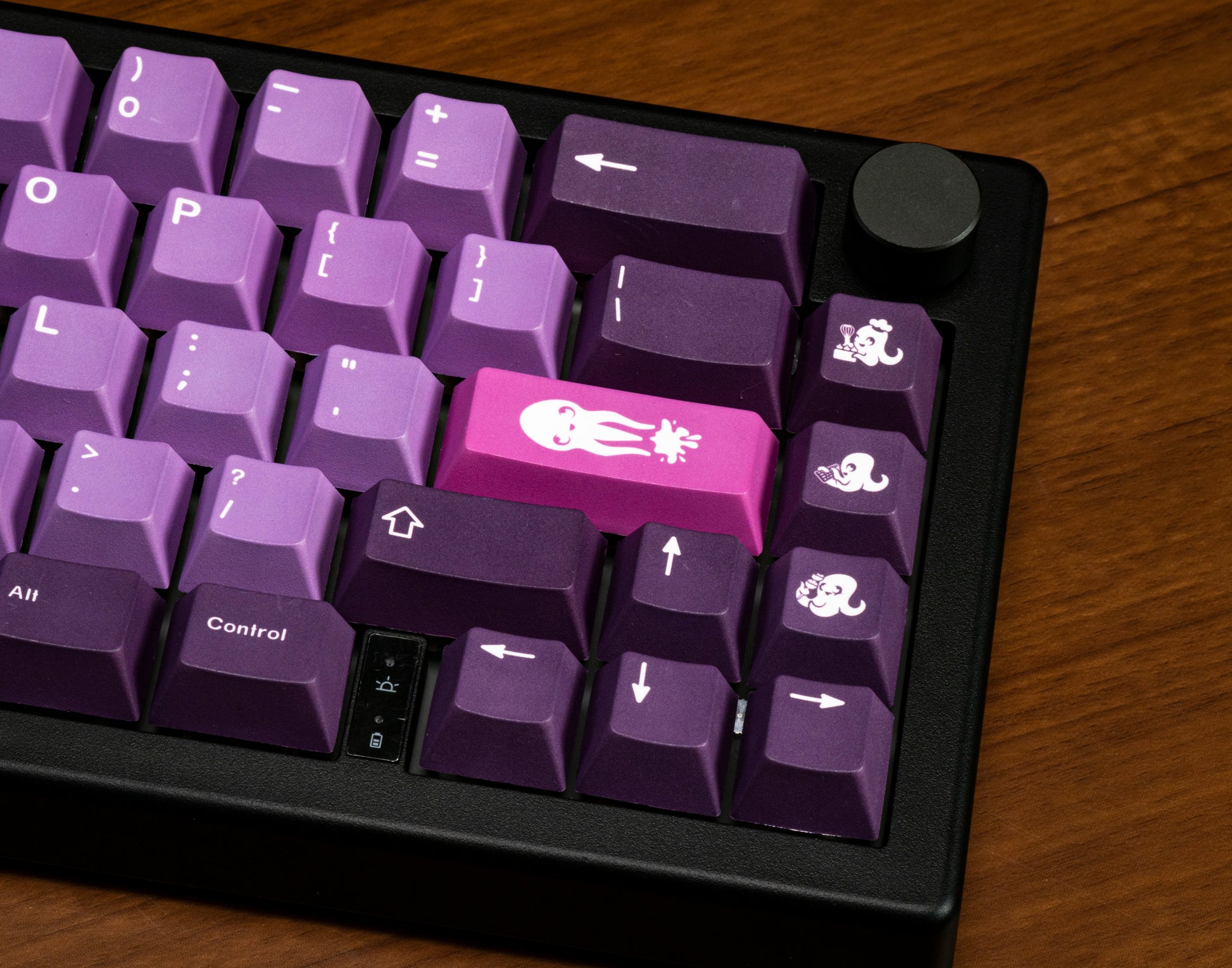Close-up of purple keycaps with octopus icon legends and arrow keys.