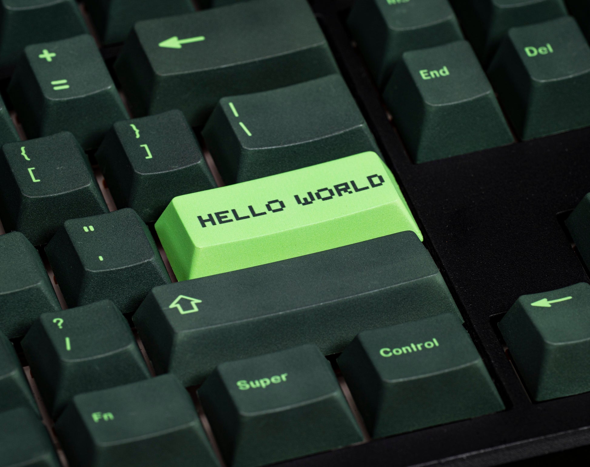 Close-up of green “Hello World” PBT keycap with surrounding dark green key legends