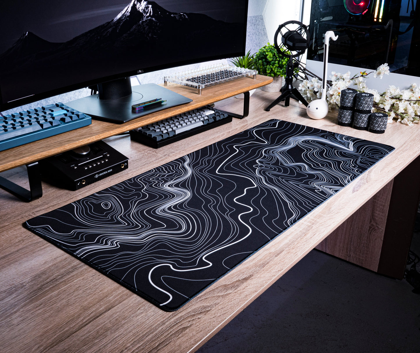 Black desk mat with white topographic contour line pattern on a desk