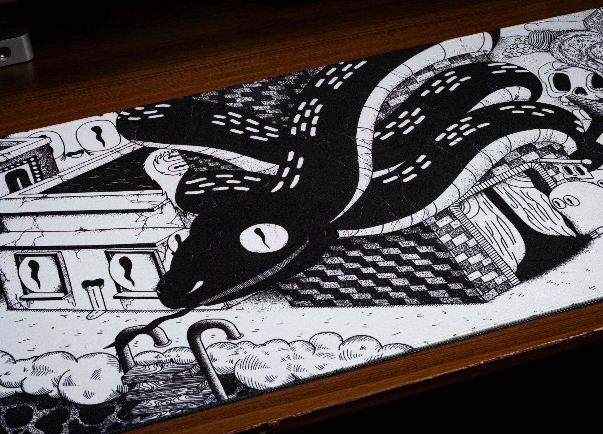 Black and white desk mat close-up with tentacle illustration and clouds