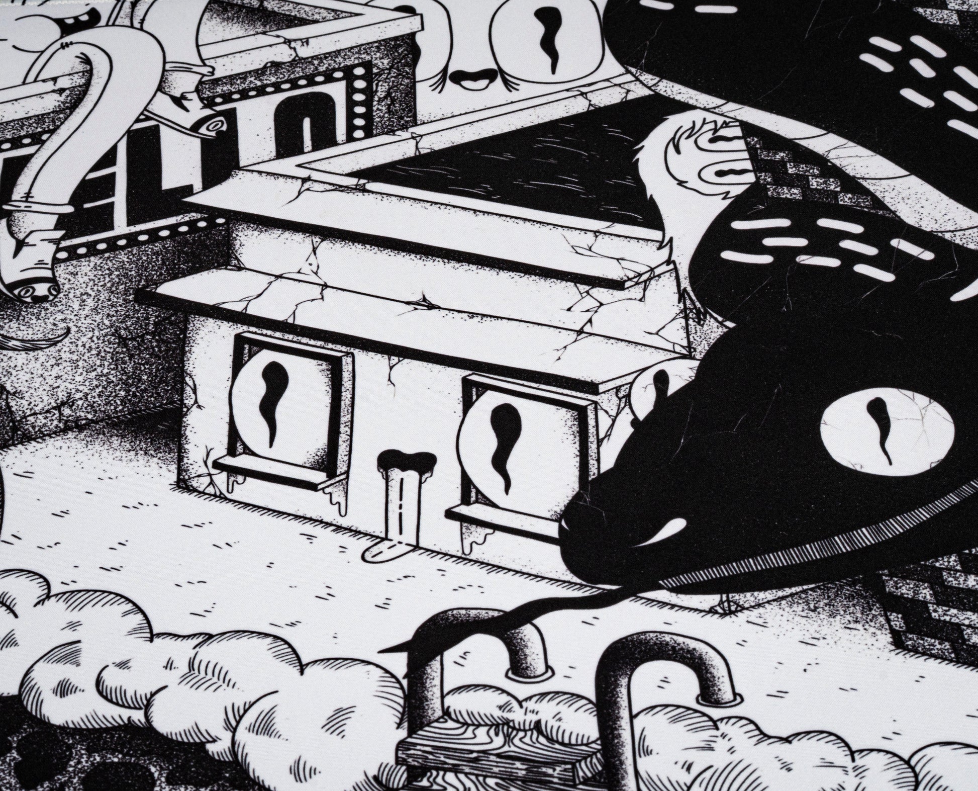 Black and white desk mat close-up showing small doors, clouds, and tentacle