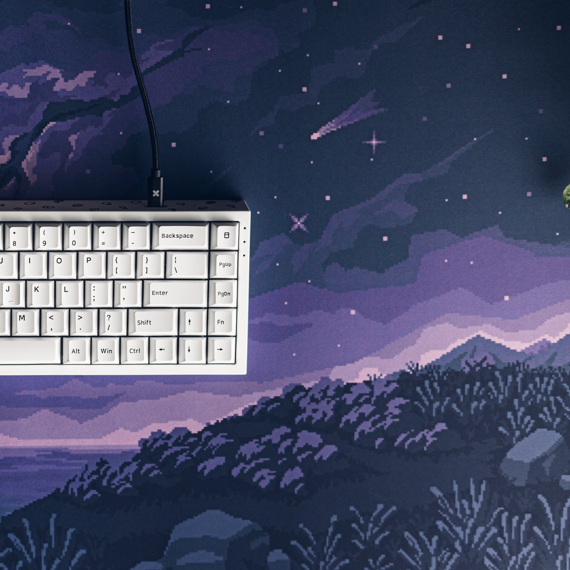 Pixel desk mat corner with starry night artwork; keyboard edge partly visible