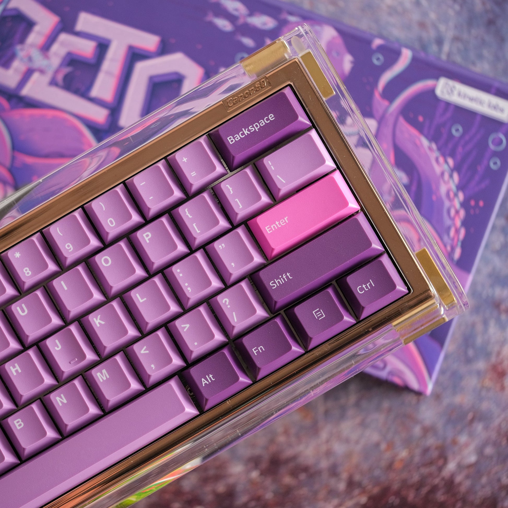 Close-up through clear box: purple octopus keycaps with Backspace and Enter.