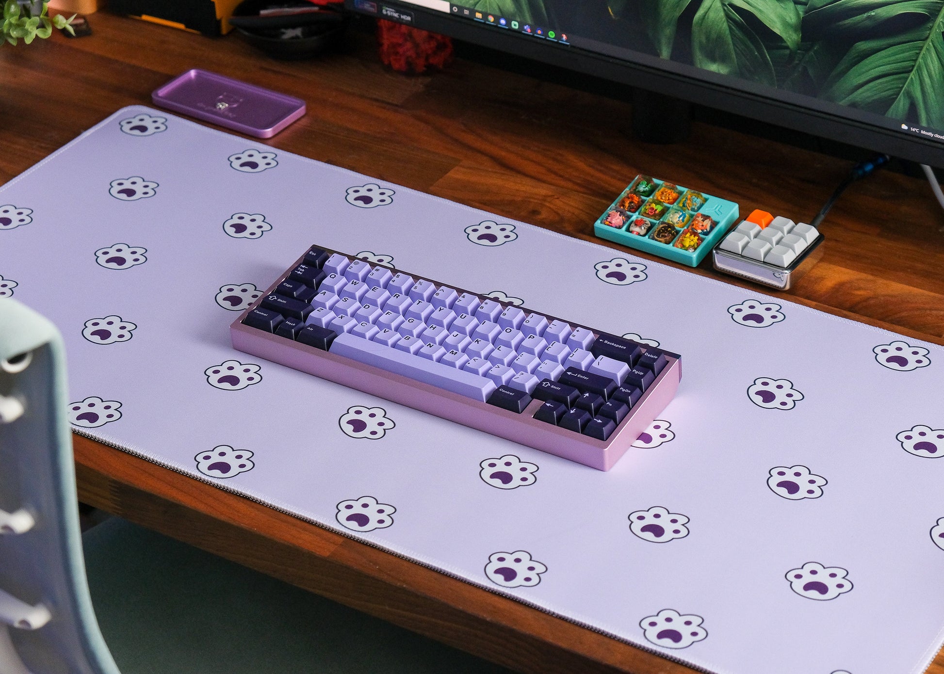 Lavender desk mat with paw-print icons, keyboard on a wooden desk