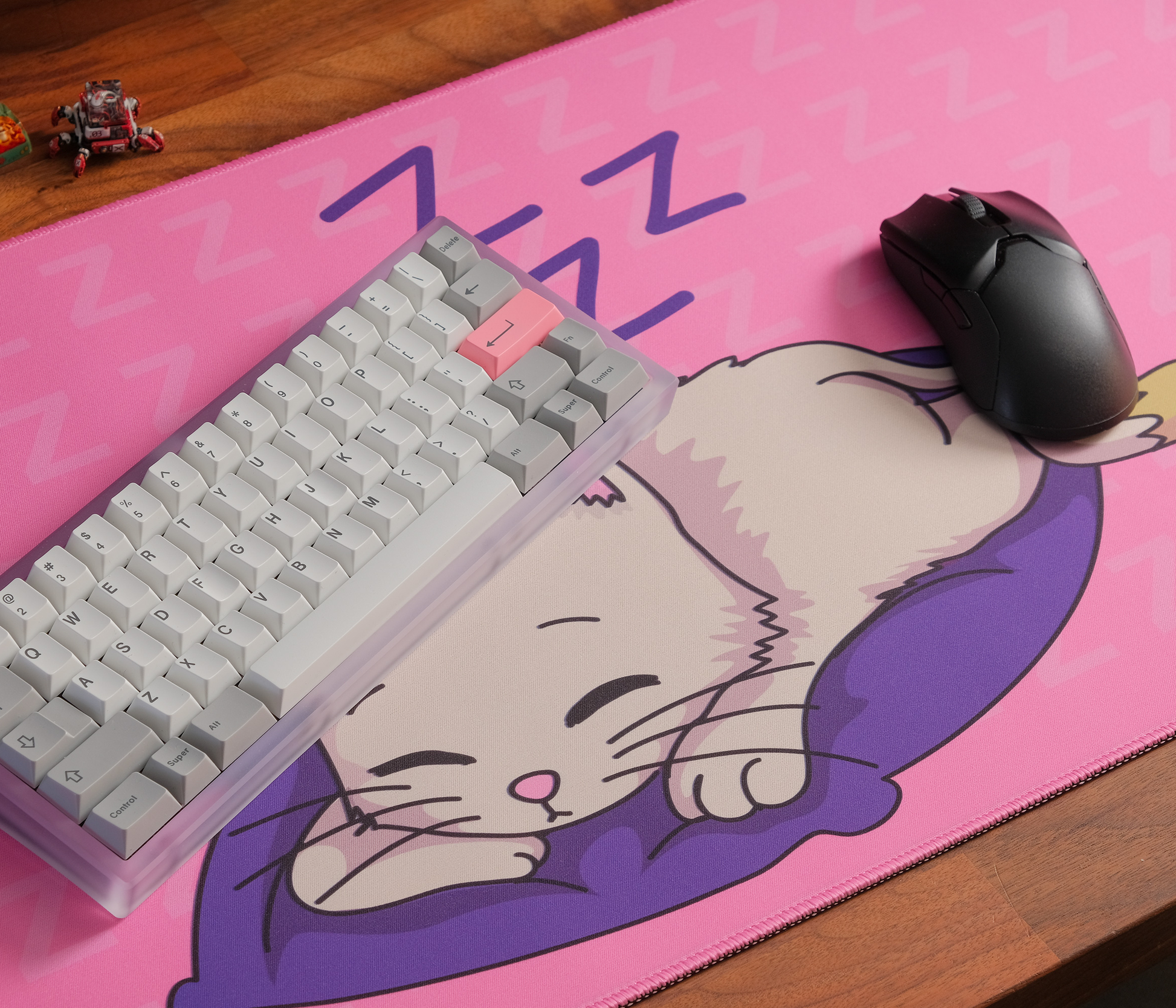 Pink desk mat with sleeping kitten illustration, ZZZ icons, and stitched border
