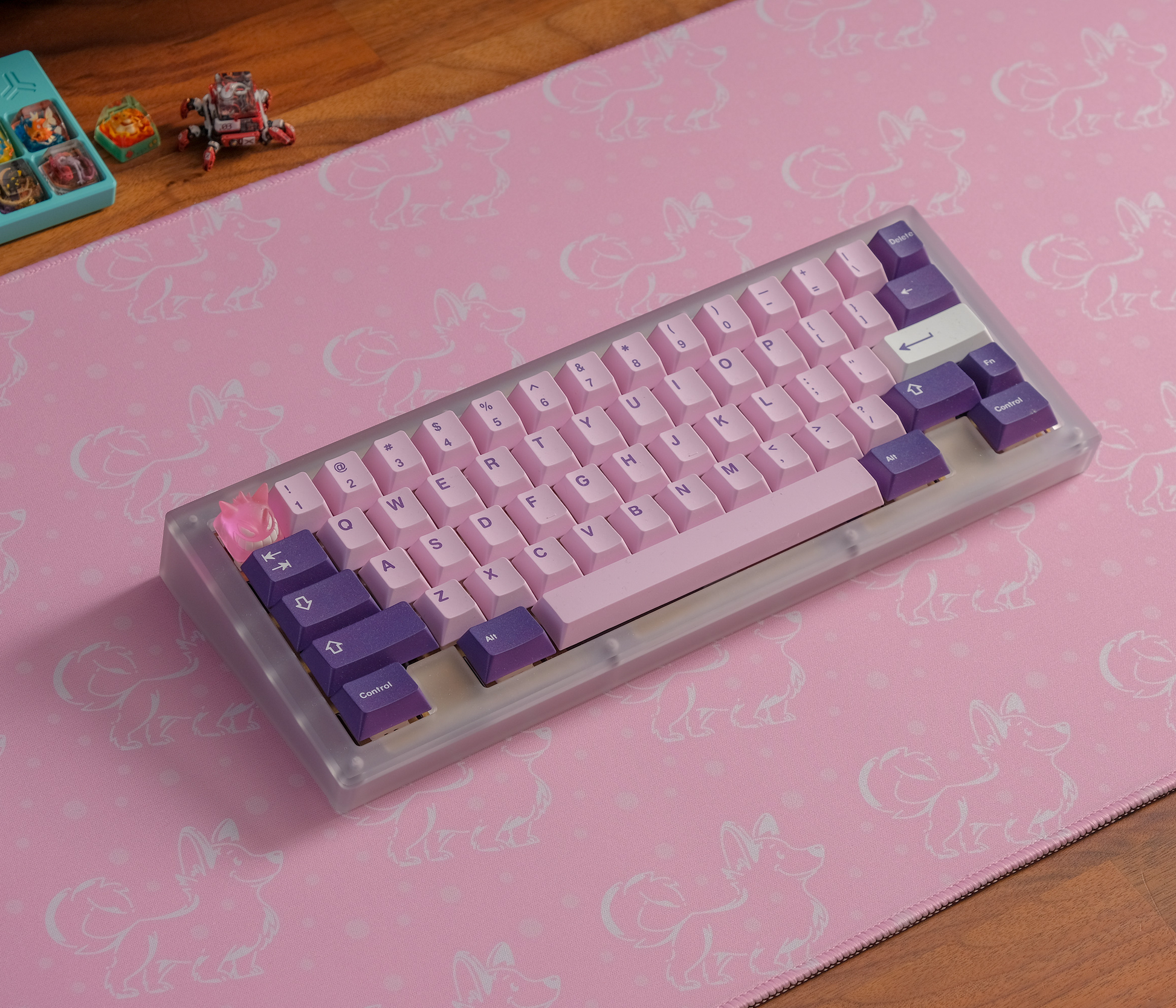 Pink desk mat with white corgi silhouettes and stitched border, keyboard angled on top