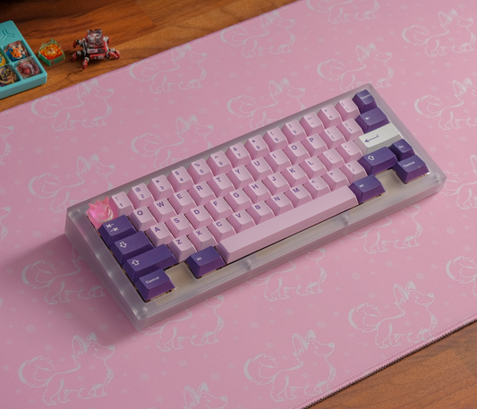Pink desk mat with white corgi silhouettes and stitched border, keyboard angled on top