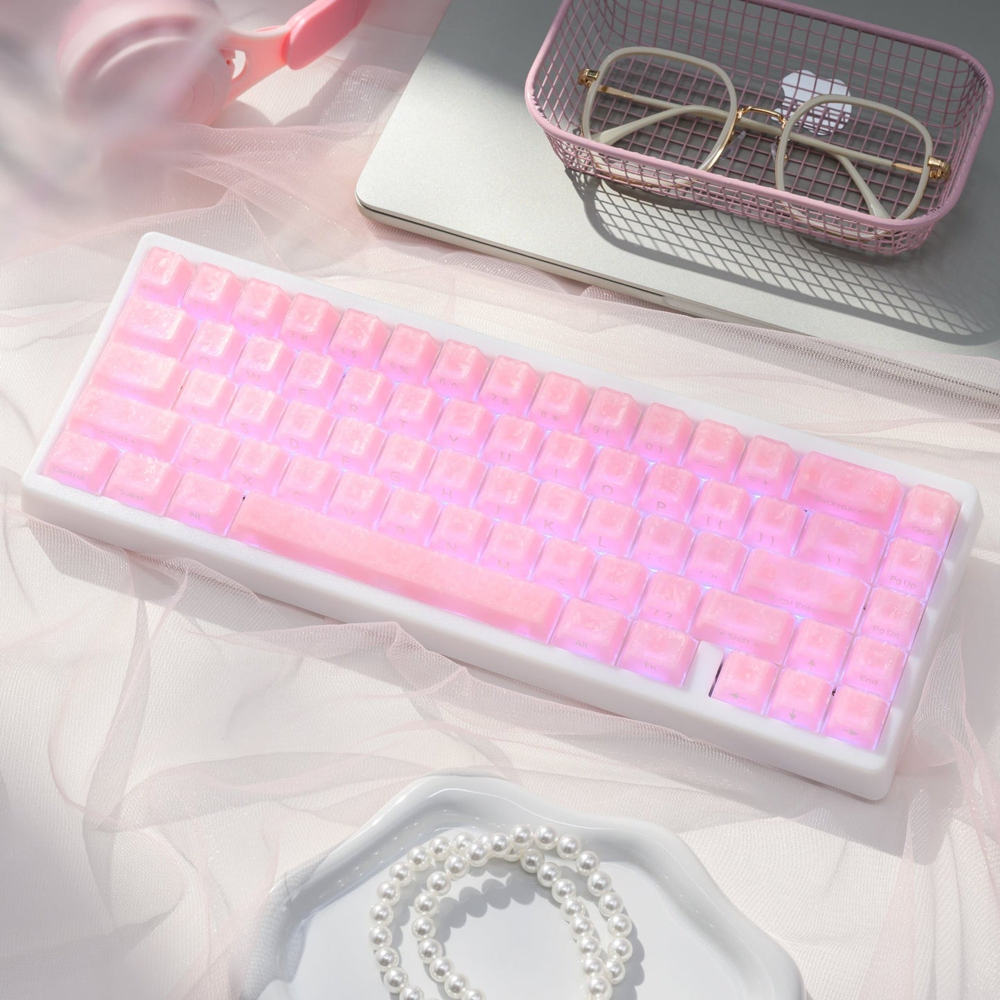 Mechanical keyboard with pink translucent keycaps, shown in a tilted view on a tray