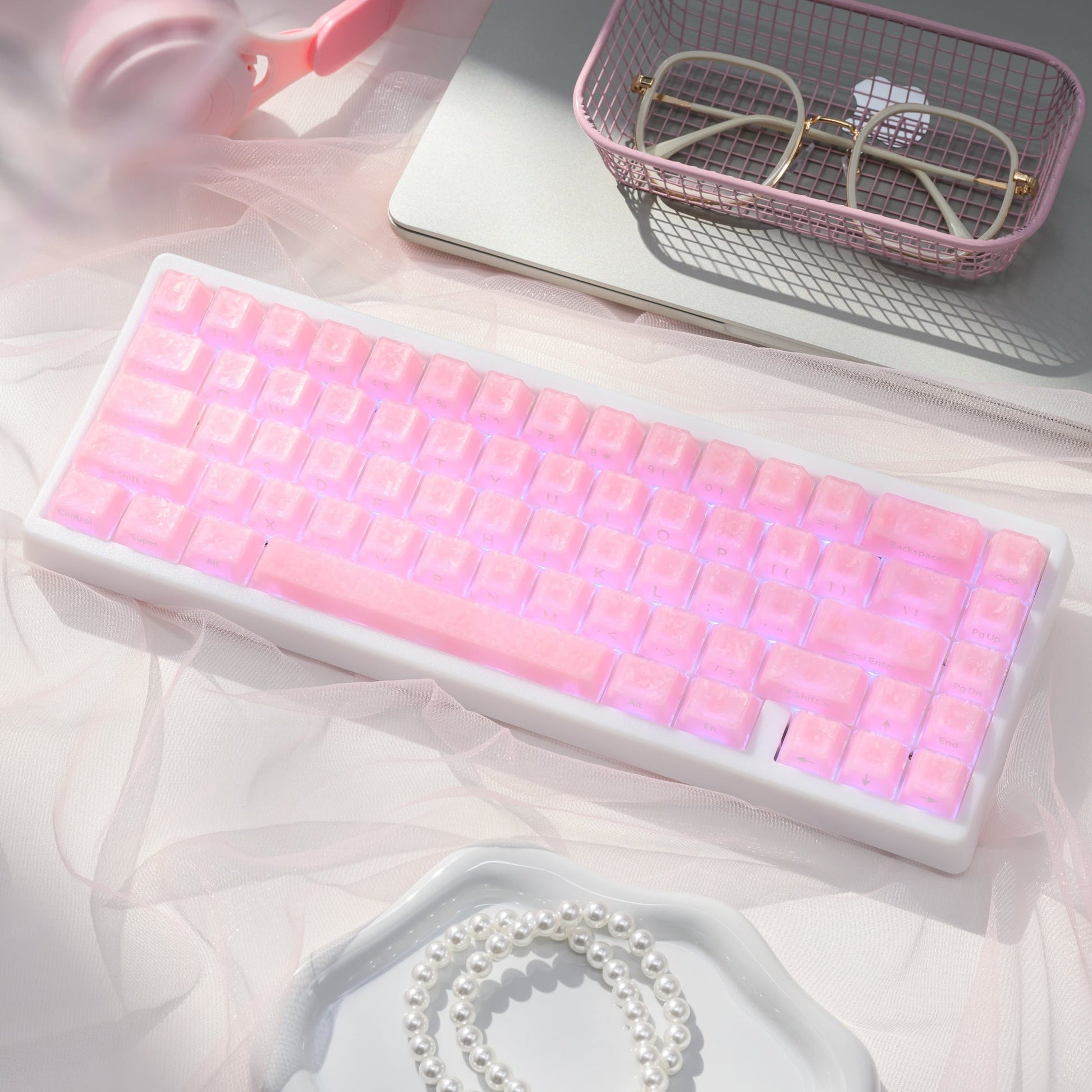 Mechanical keyboard with pink translucent keycaps, shown in a tilted view on a tray