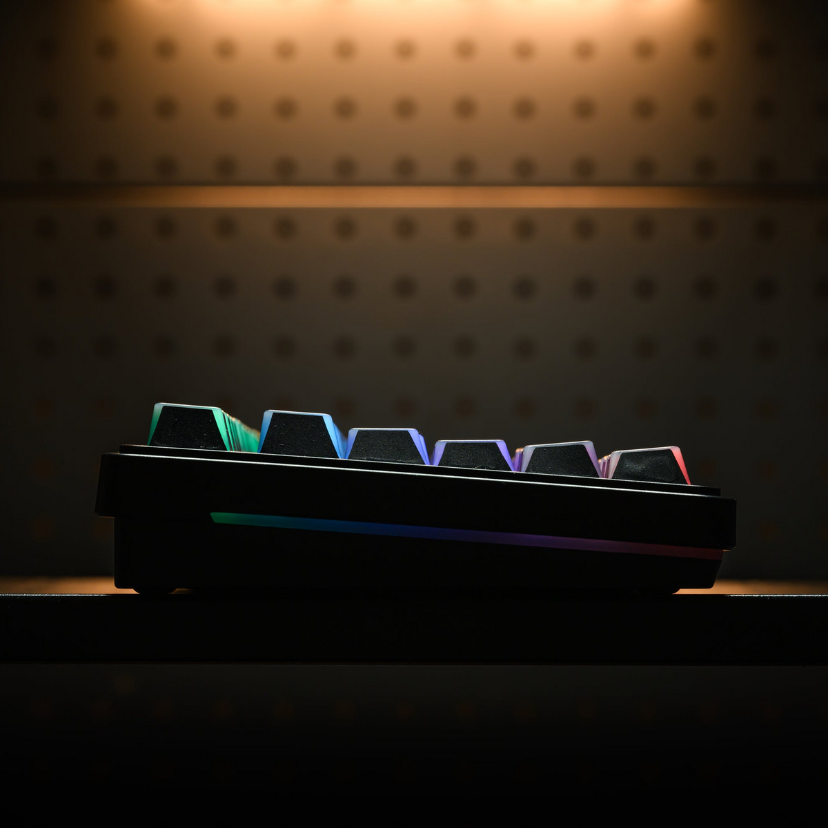 Side view of keyboard keycaps with multicolor shine-through glow along the row