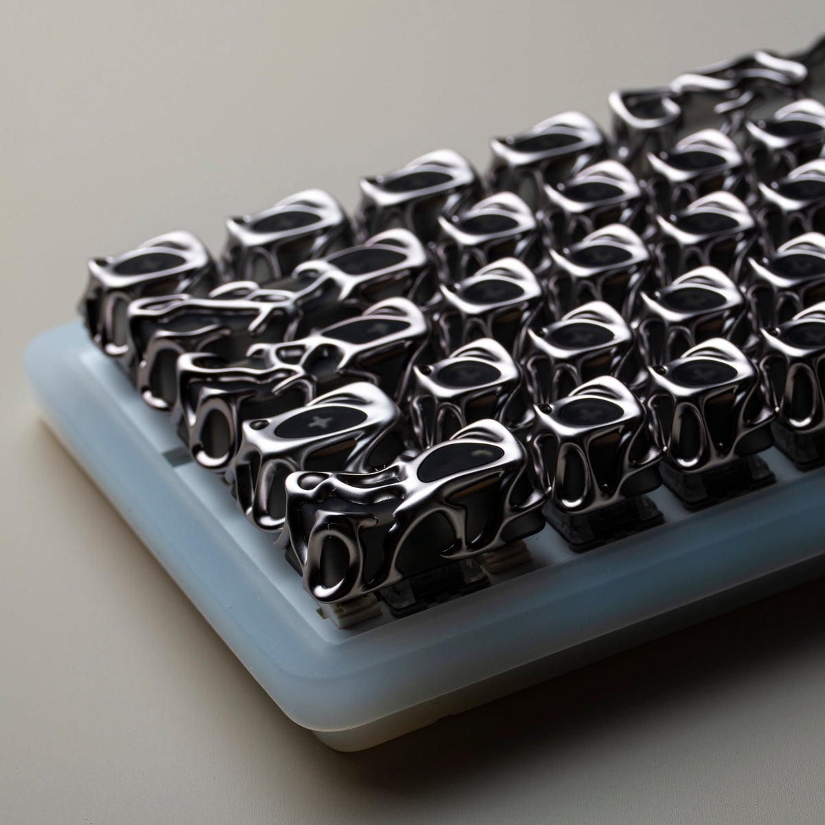 Silver liquid metallic keycap set, close-up on light-blue tray