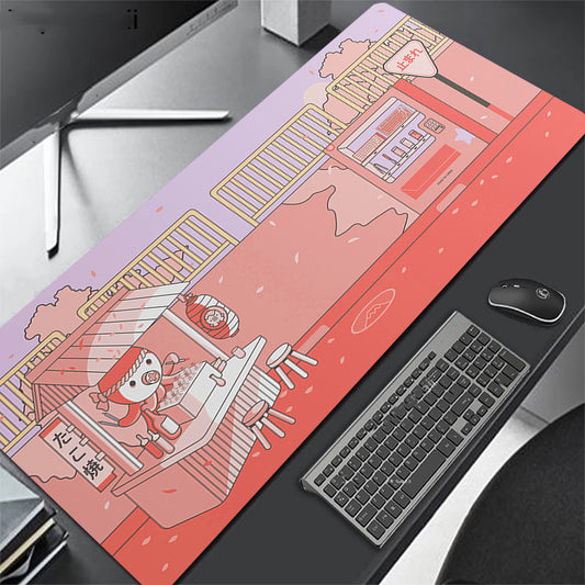 pink desk mat with cartoon design on a desk with keyboard and octopus.