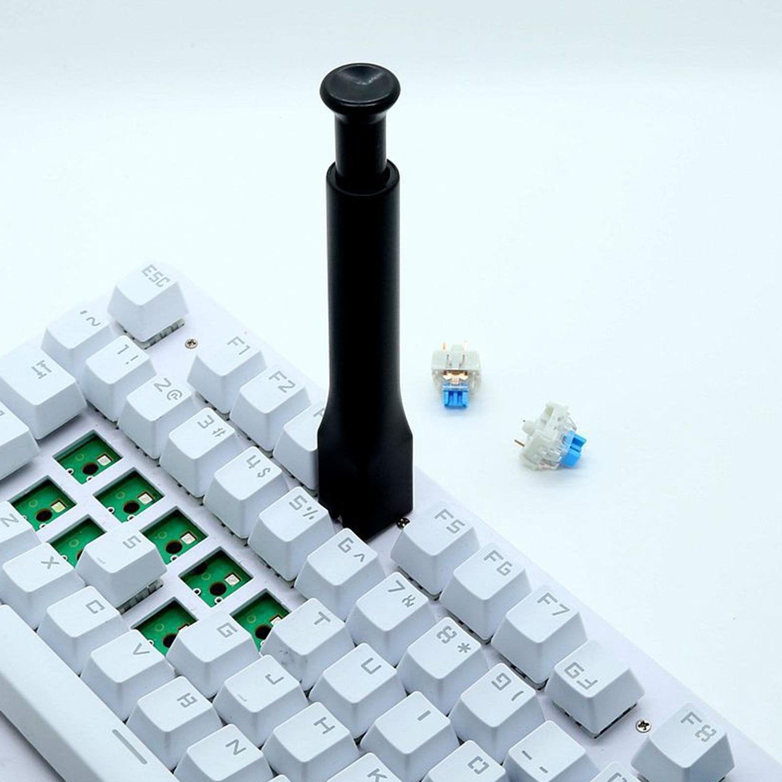 Black keyboard switch remover tool with plunger tip above keycaps
