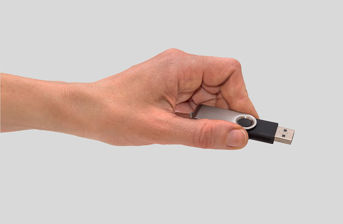USB 2.0 flash drive held in a hand, silver metal body with black swivel cap