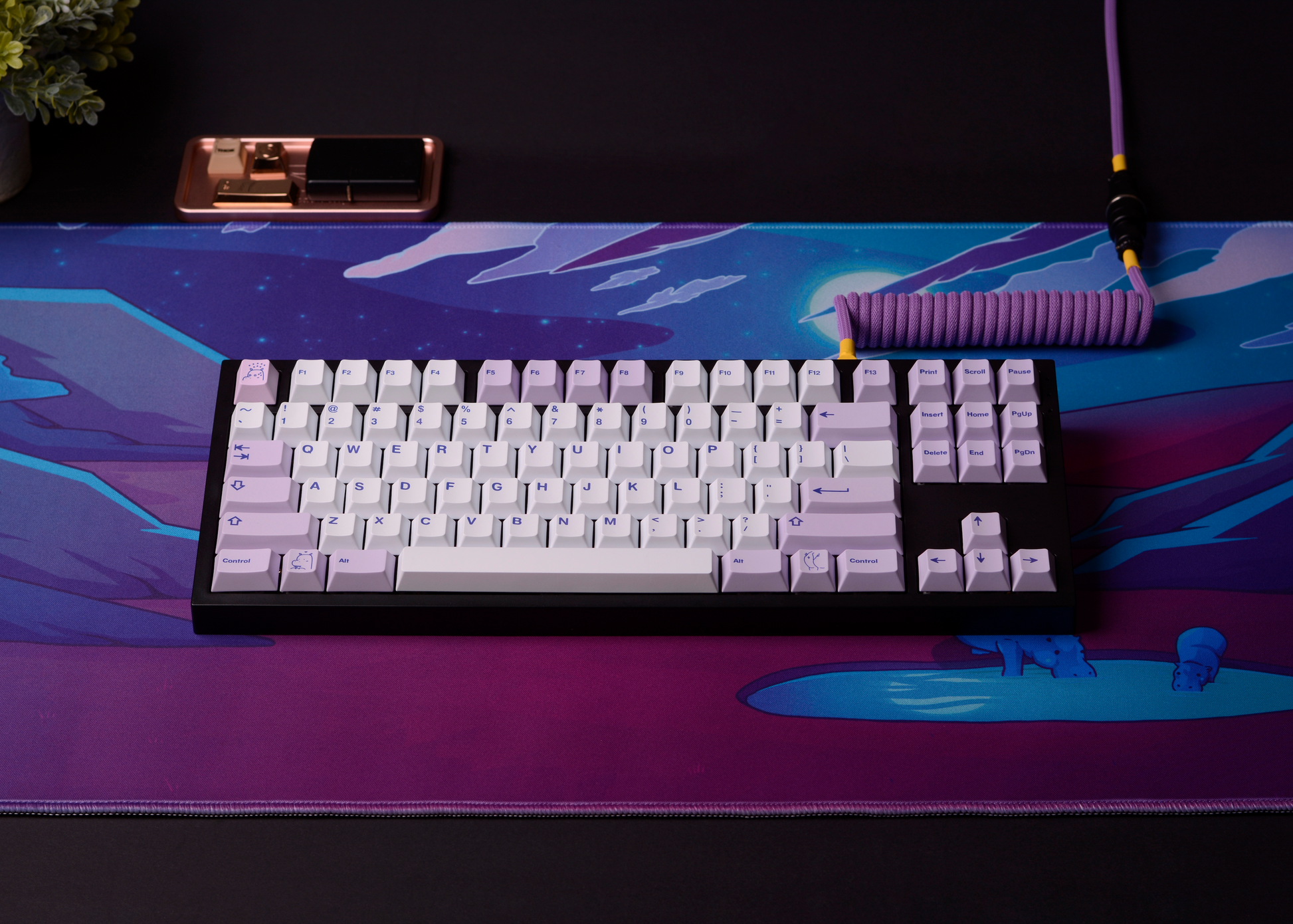 Desk mat with neon sci-fi artwork and keyboard centered; blue creatures at right