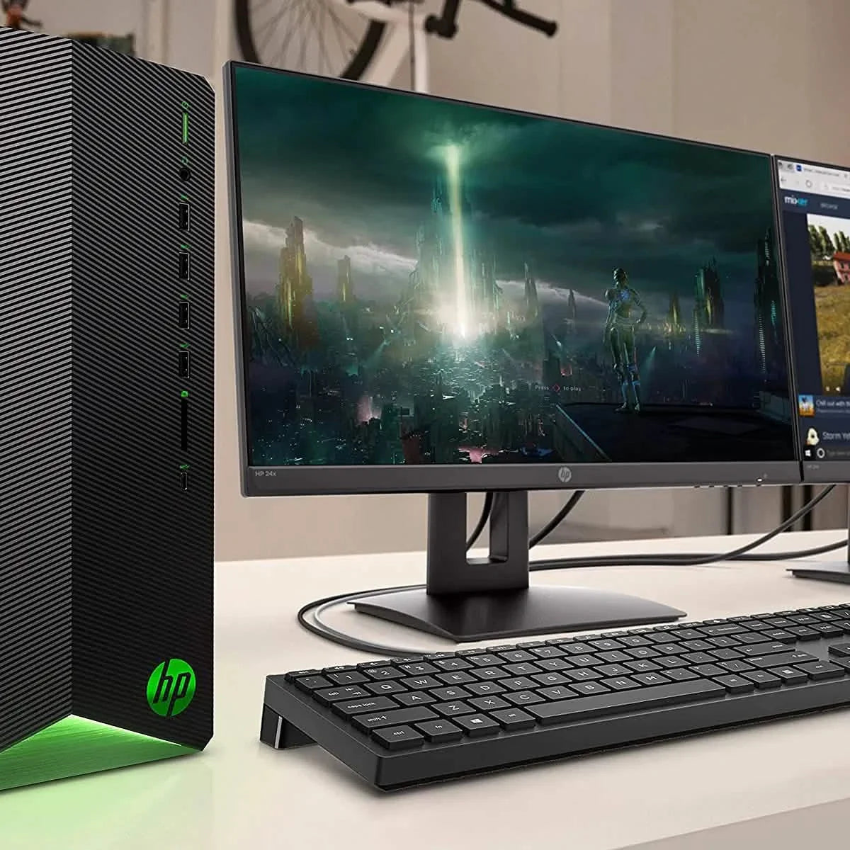 Black desktop tower with ribbed side and green-lit base near keyboard and display