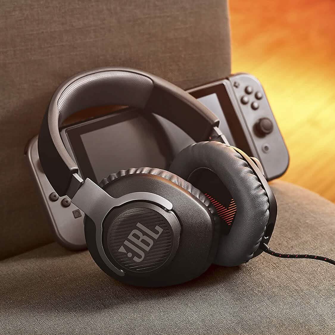 JBL Quantum 100 wired over-ear headphones resting on a couch seat