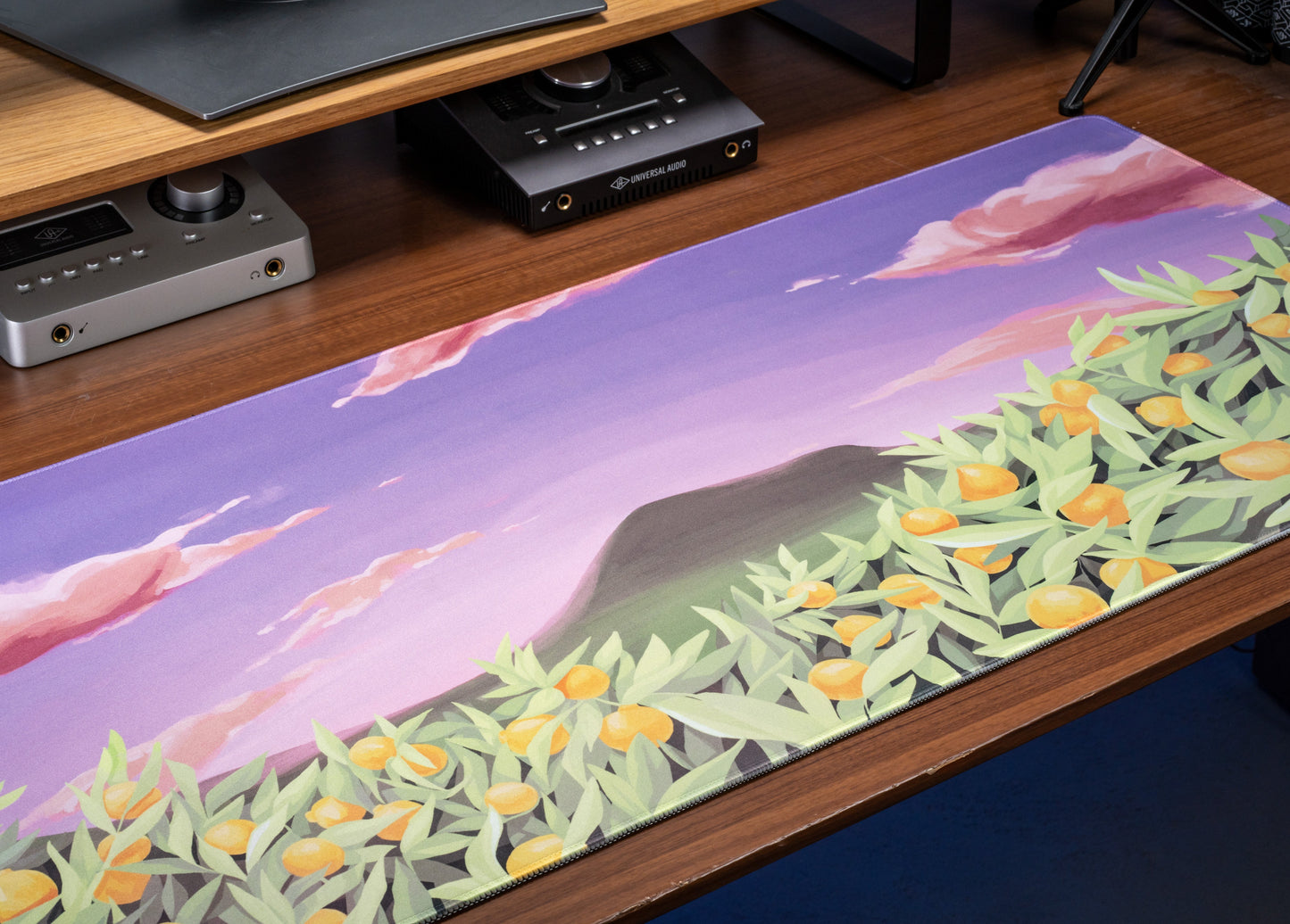 Desk mat with lavender mountain scene and scattered citrus blossoms in green and orange