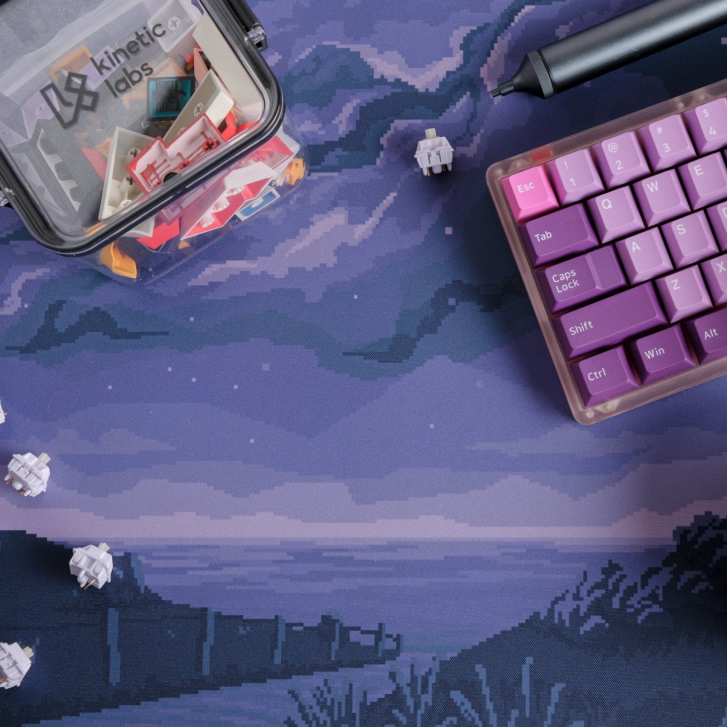 Purple cosmic pixel desk mat with clouds and horizon; keyboard edge partly visible
