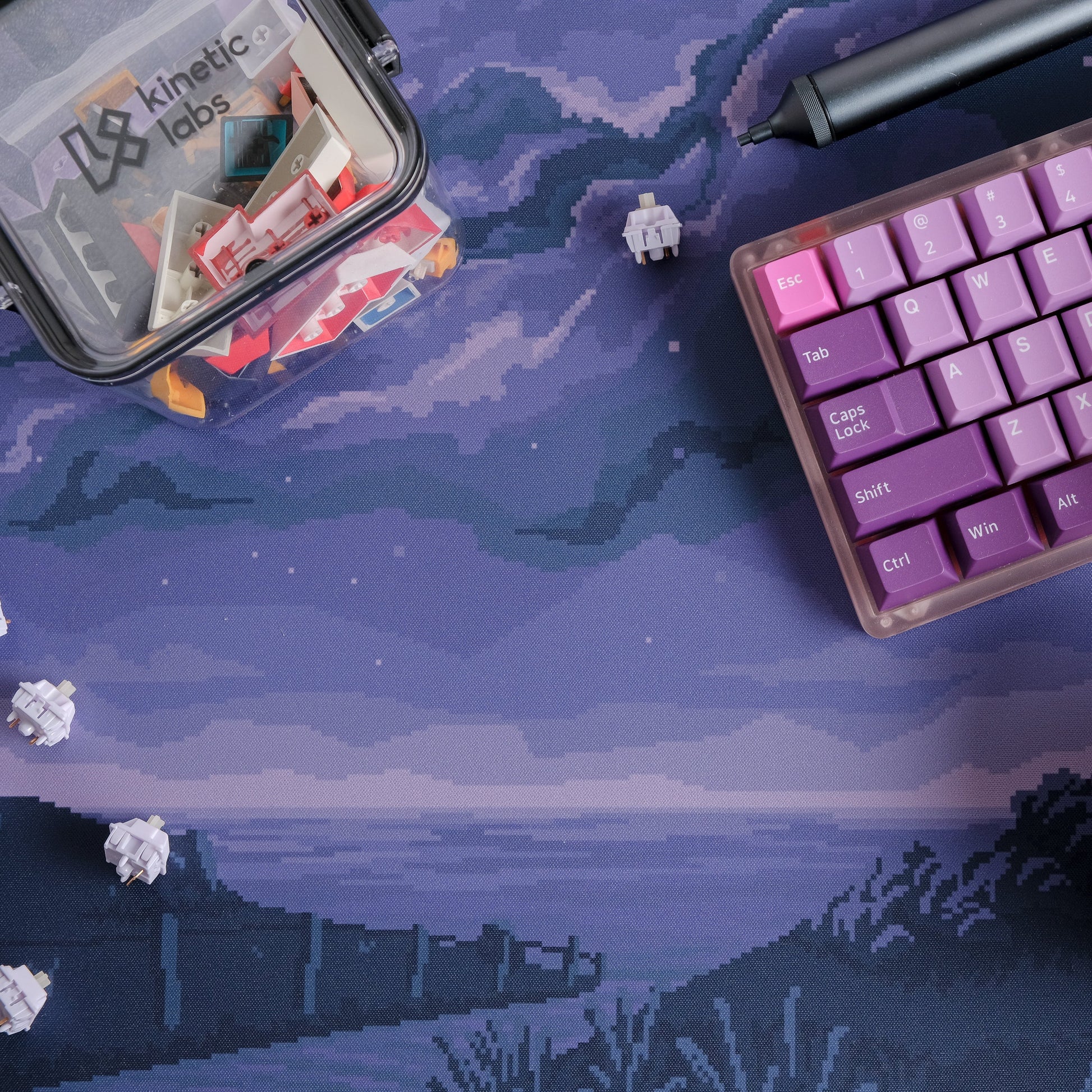 Purple cosmic pixel desk mat with clouds and horizon; keyboard edge partly visible